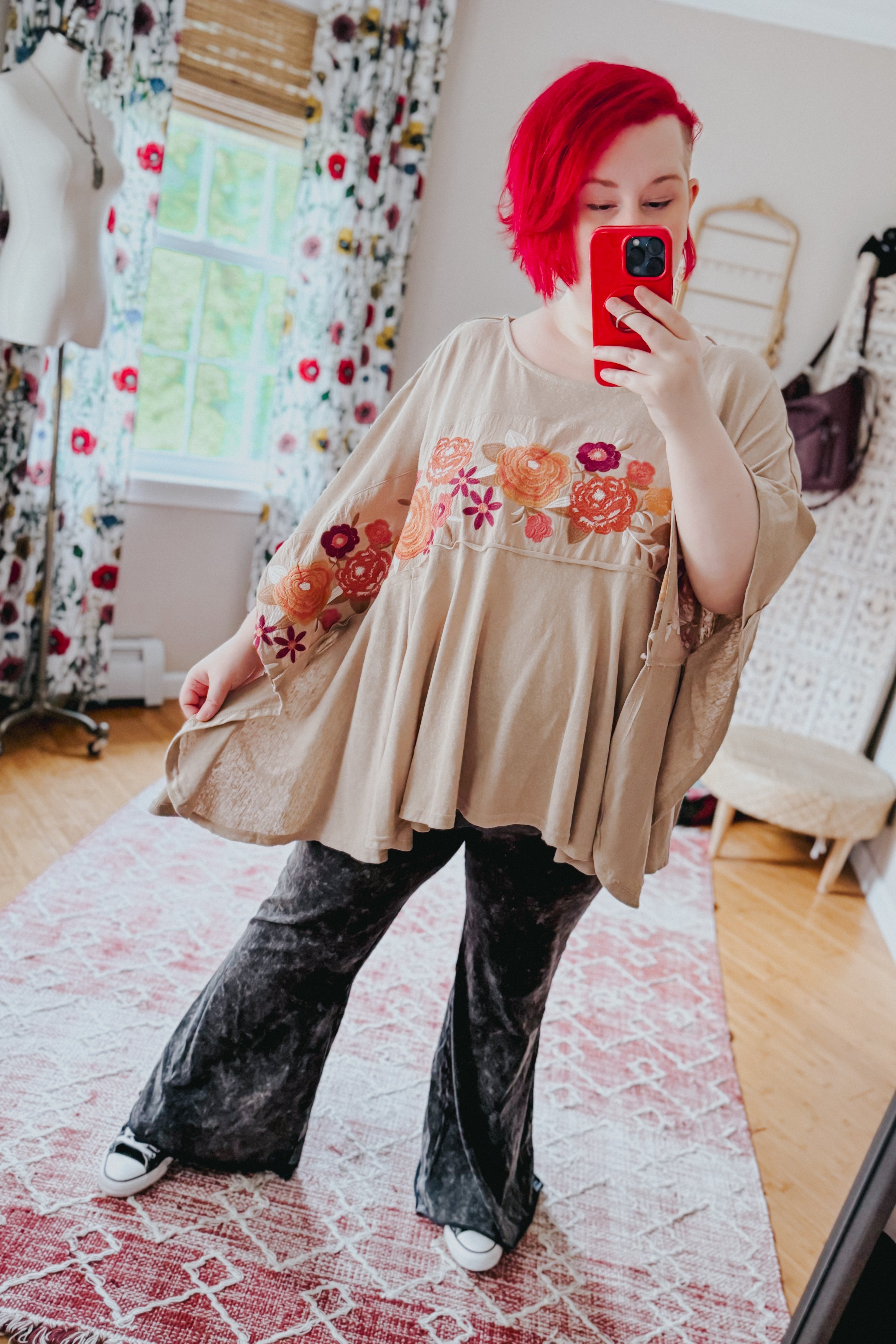 Woman taking mirror selfie wearing mocha Isabel embroidered tunic with floral designs and loose fit paired with black pants
