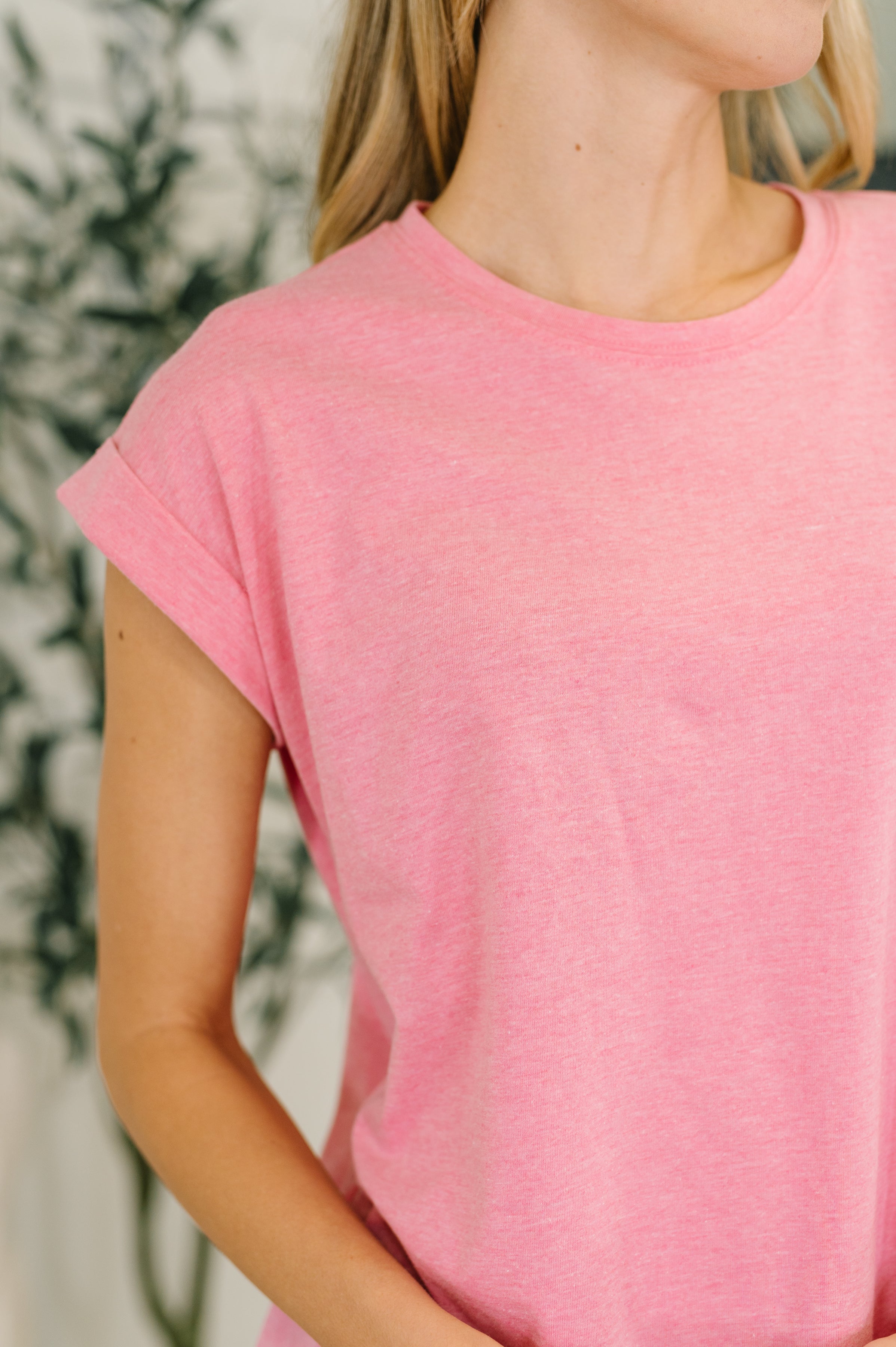Close-up of woman wearing a soft pink rolled sleeve basic tee with a round neckline indoors