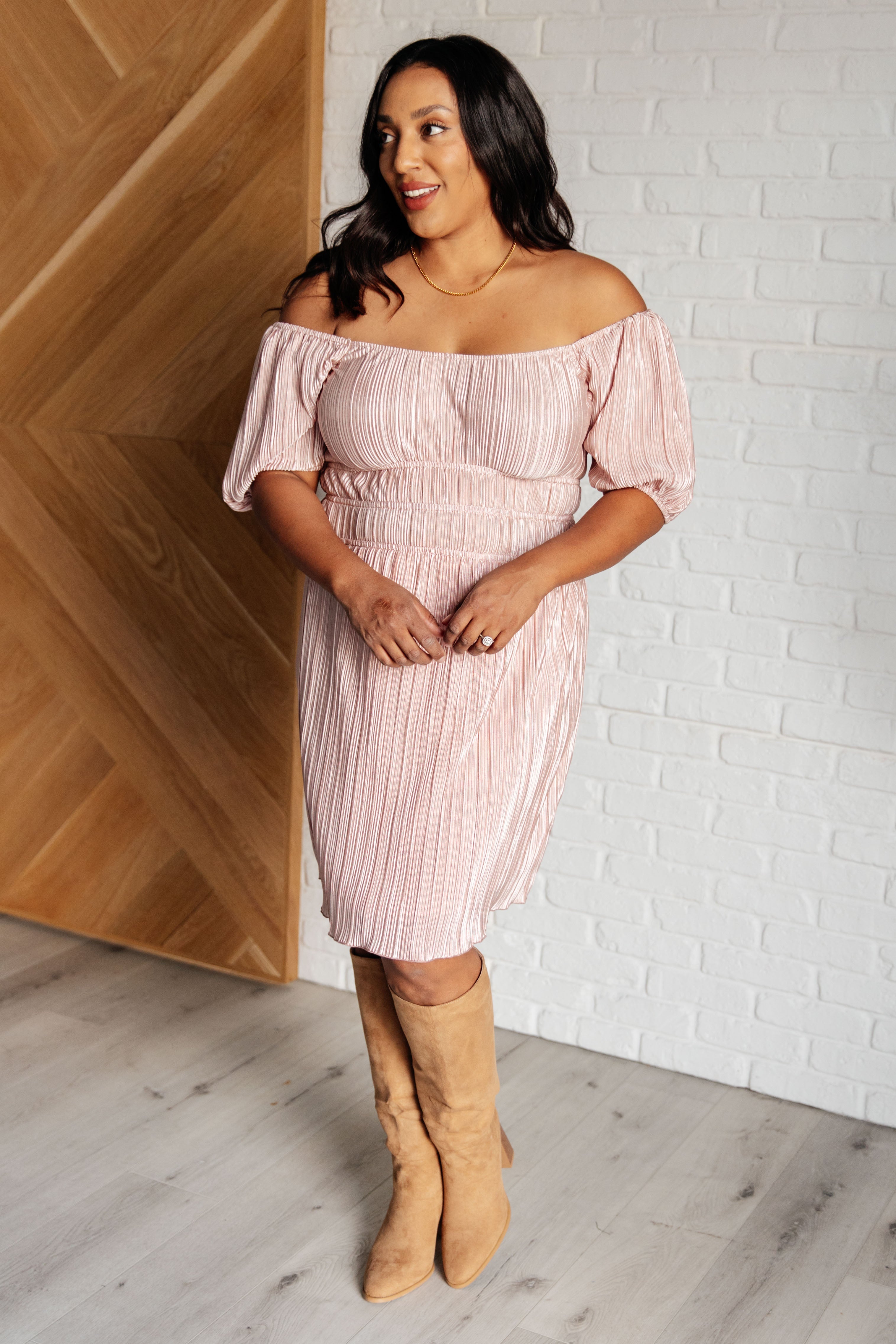 Woman wearing a pink off-the-shoulder dress with gathered waist and elbow-length balloon sleeves indoors