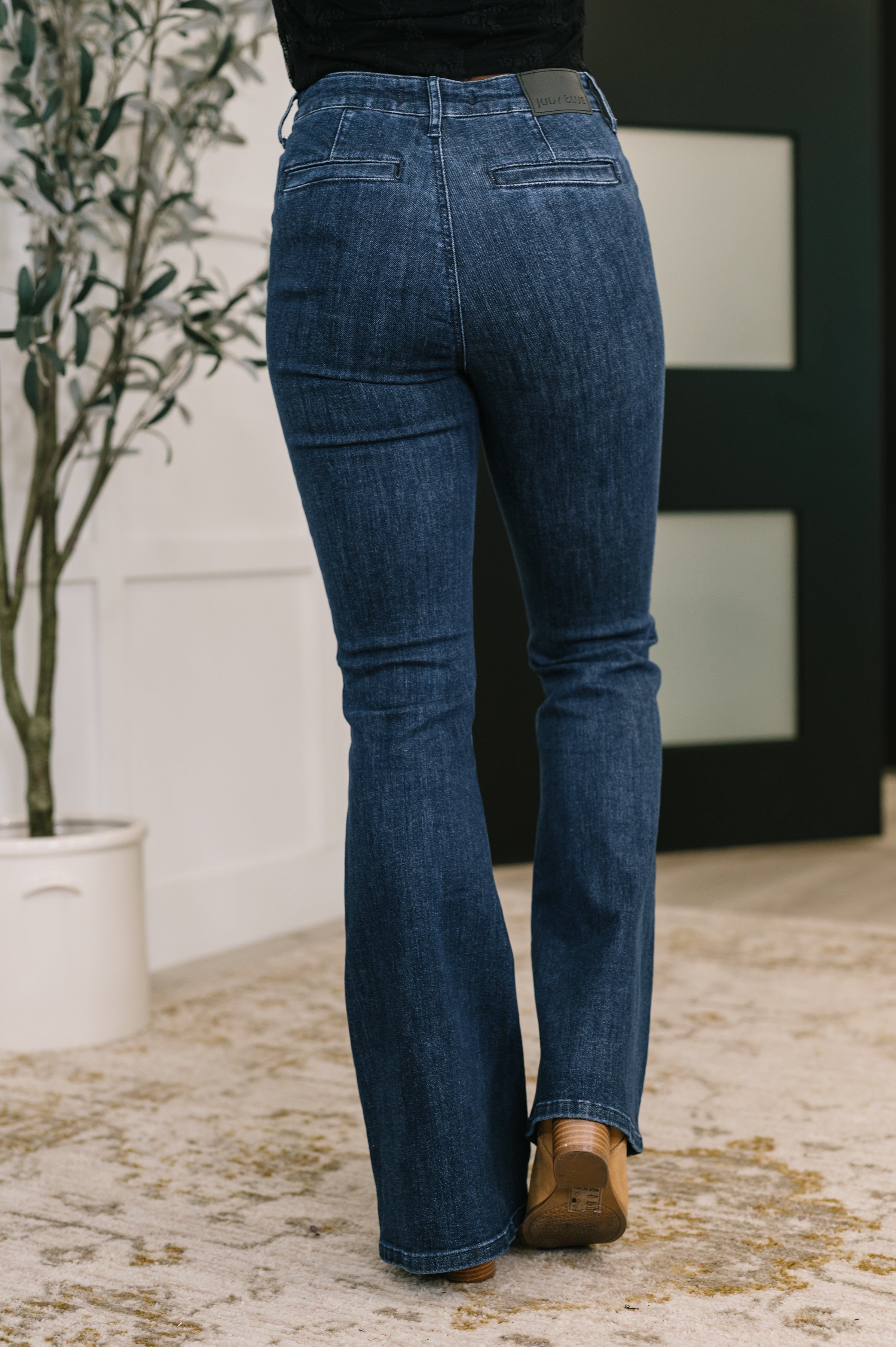 Back view of person wearing blue Jada high waist flare jeans with patch pockets standing indoors