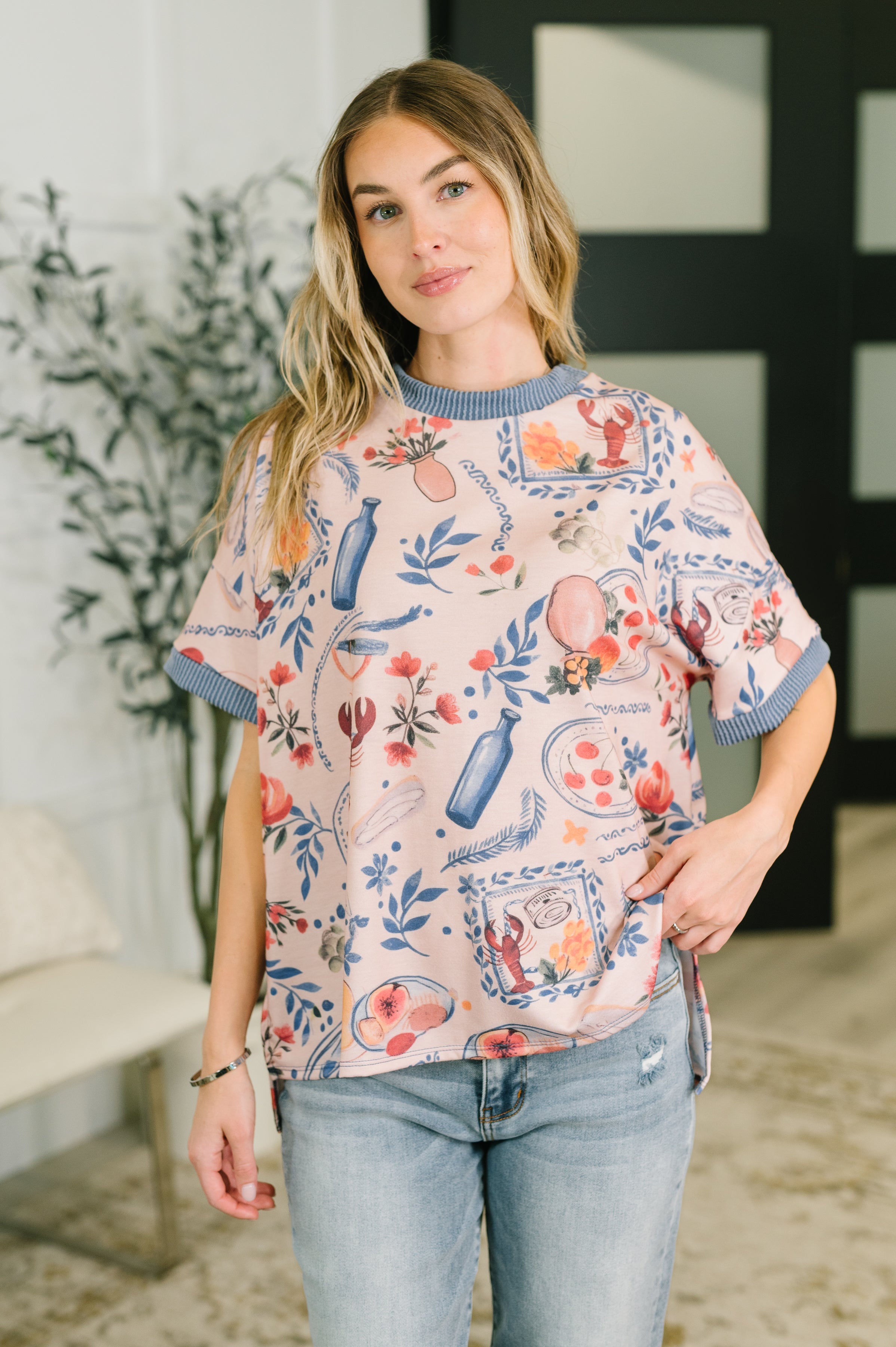 Woman wearing a pastel graphic tee with blue ribbed trim and casual light-wash jeans indoors