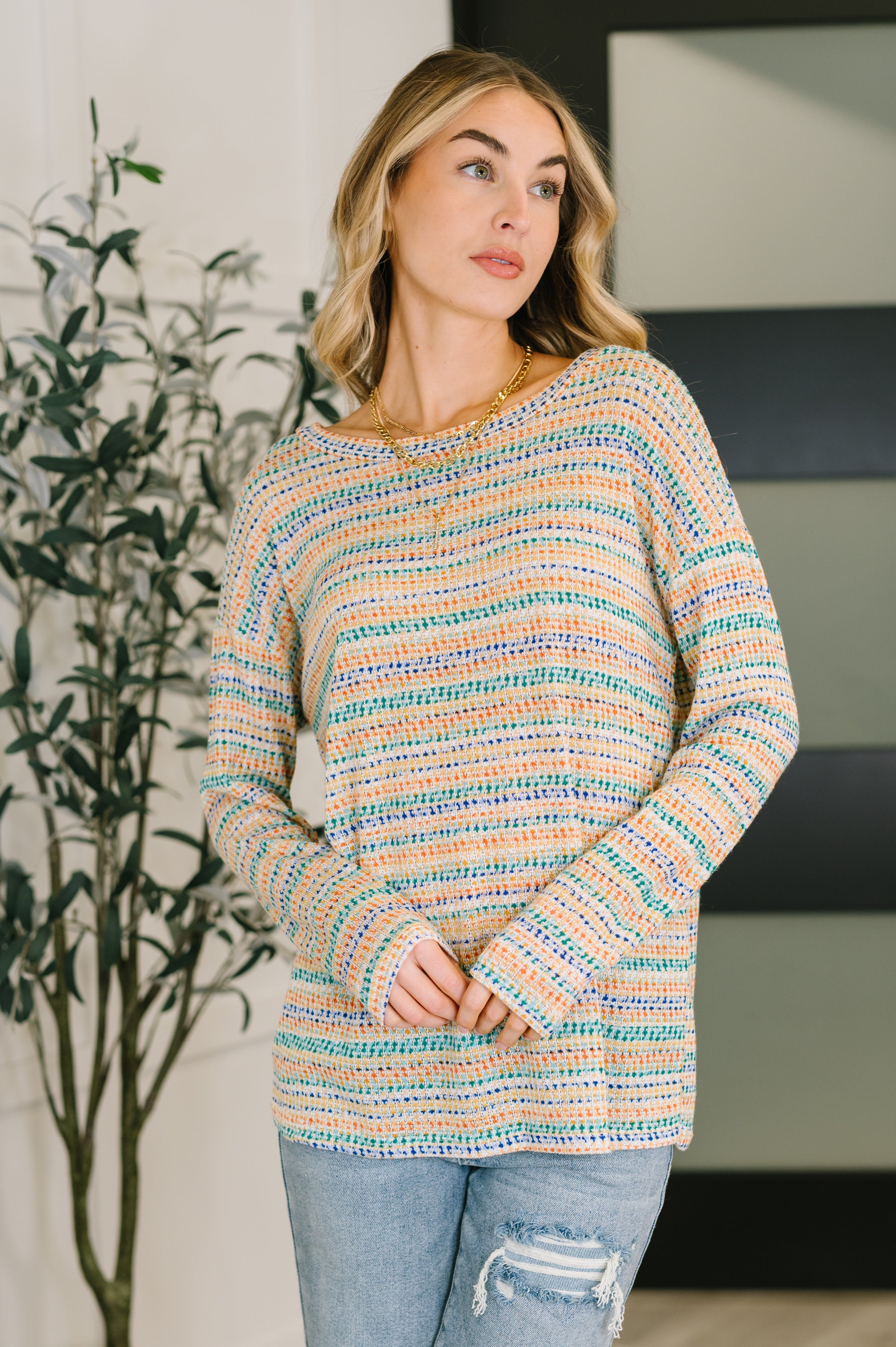 Woman indoors wearing multi Just About Right Top with a relaxed fit and horizontal stripe pattern paired with distressed jeans