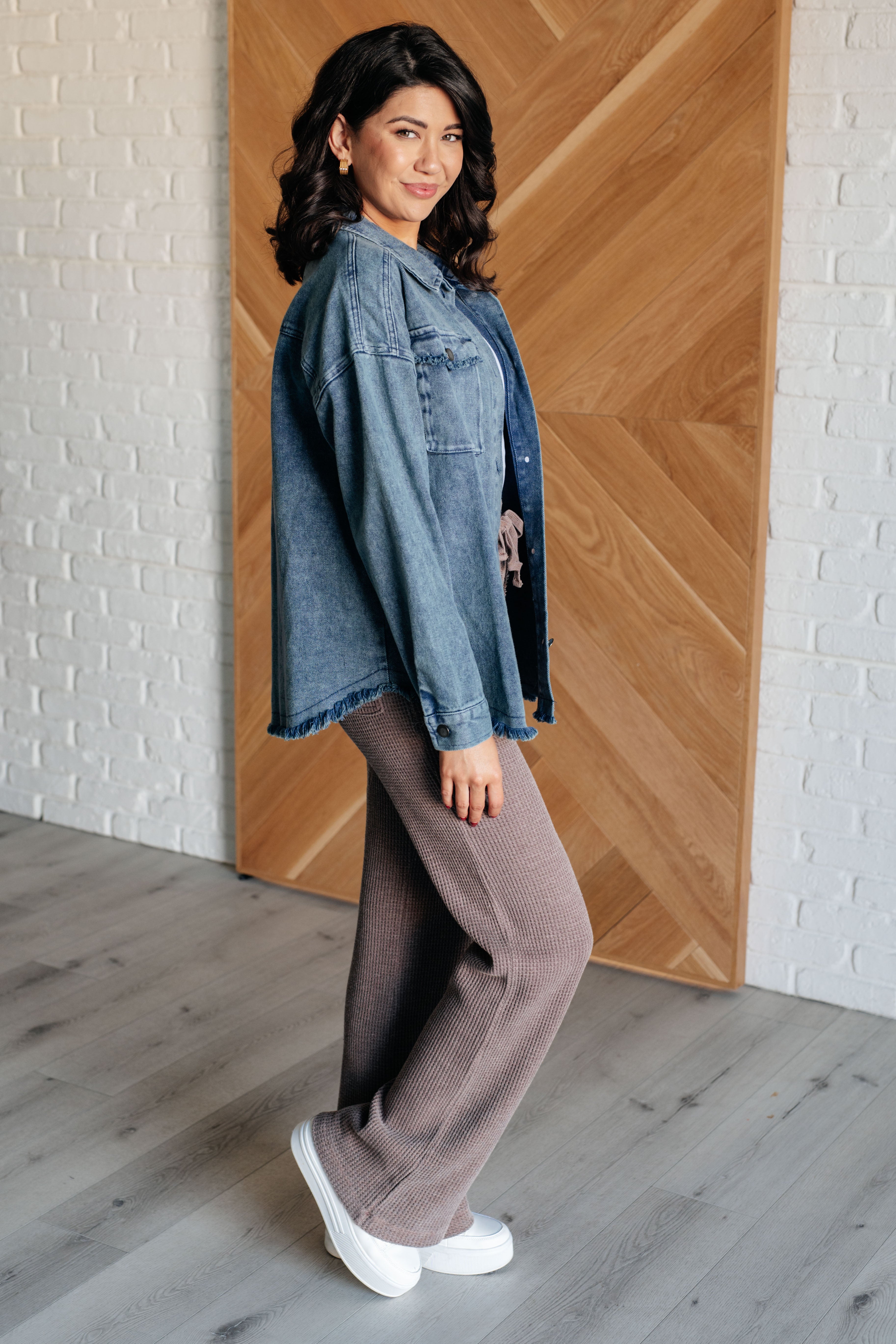 Woman posing indoors wearing blue Just In Case Mineral Wash Shacket with relaxed fit and frayed hem paired with textured brown pants