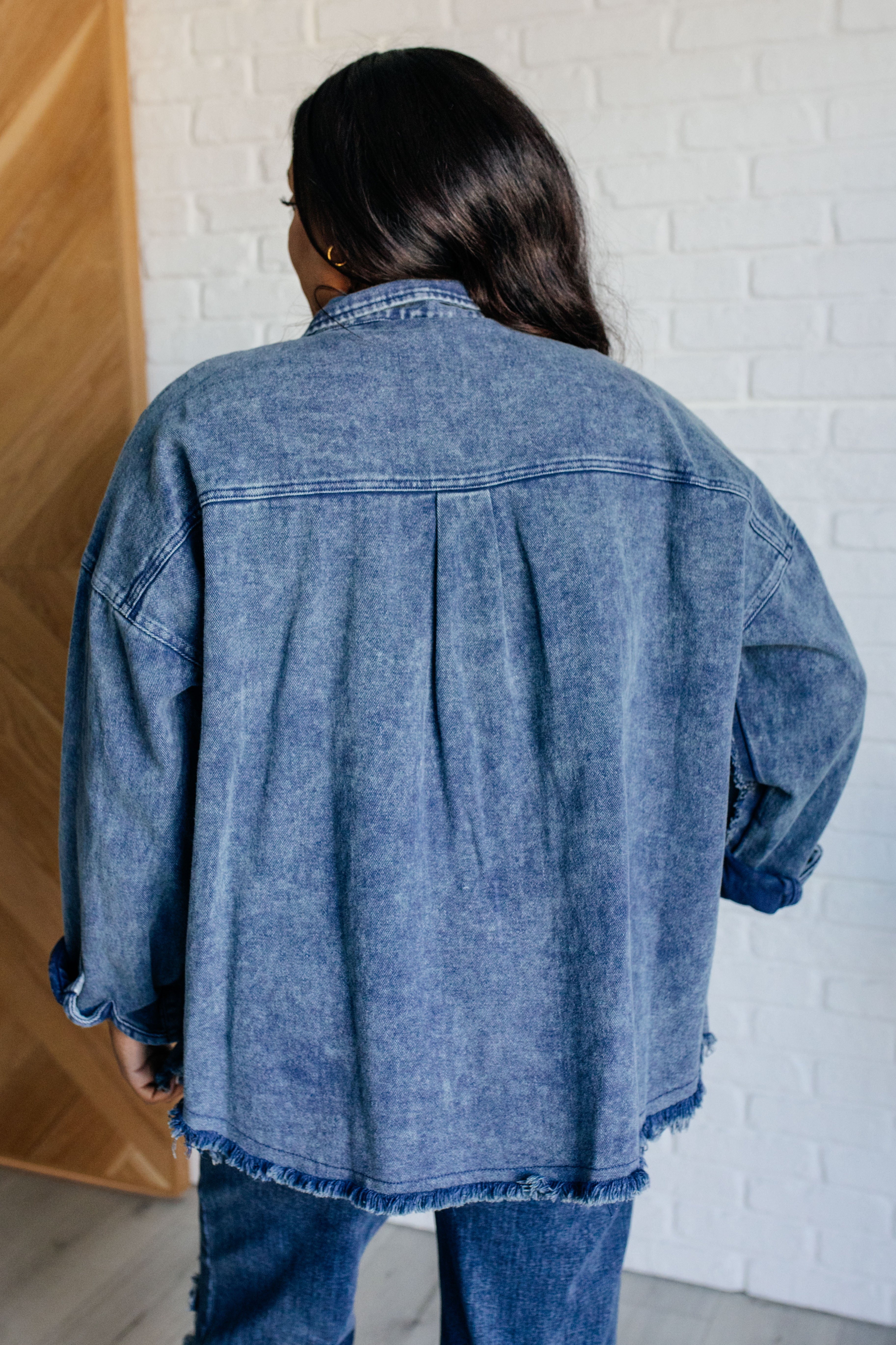 Woman indoors wearing blue Just In Case Mineral Wash Shacket with relaxed fit and frayed hem paired with matching denim jeans