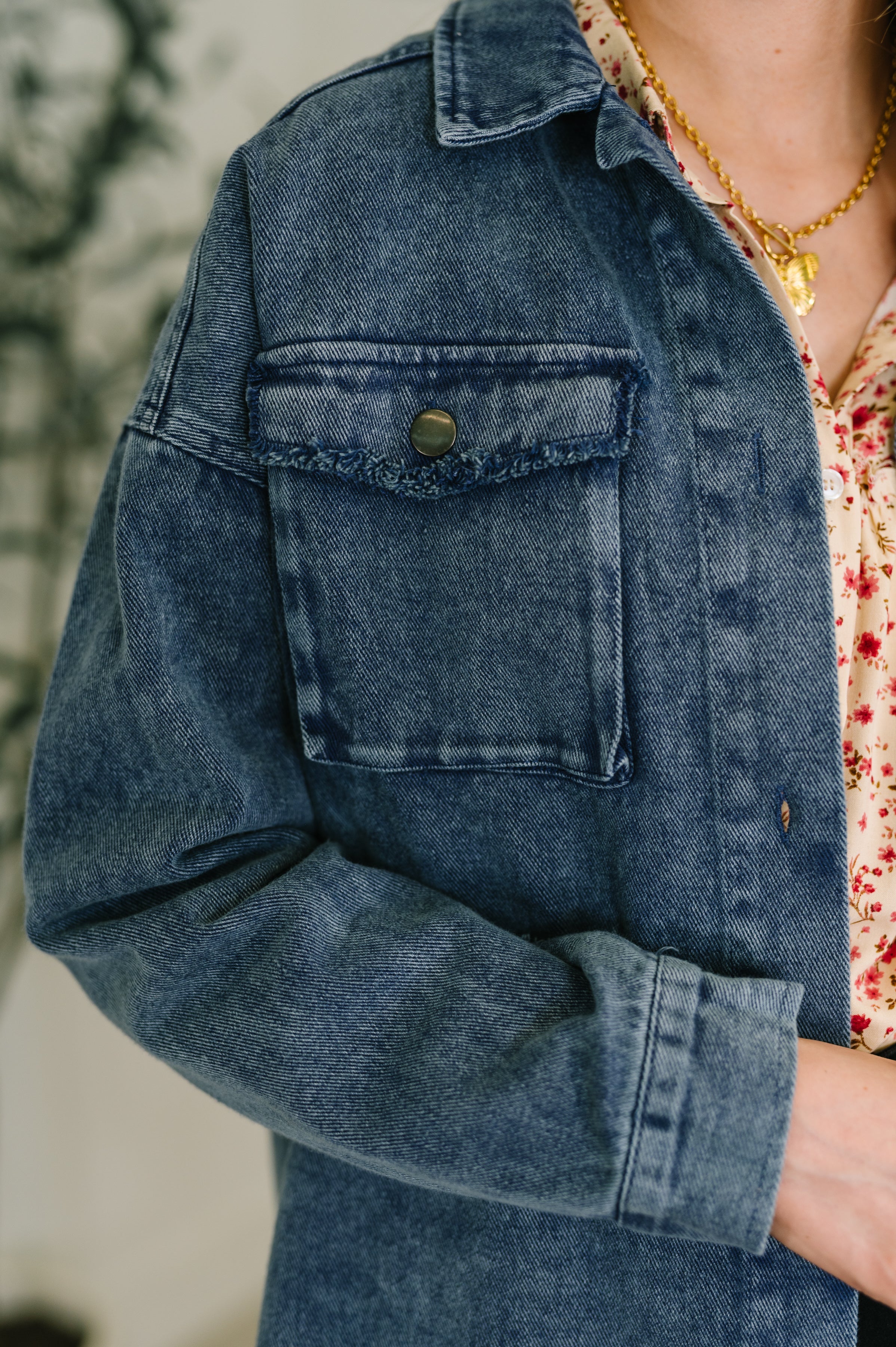 Close-up of blue Just In Case Mineral Wash Shacket featuring textured chest pocket and button detailing over floral top