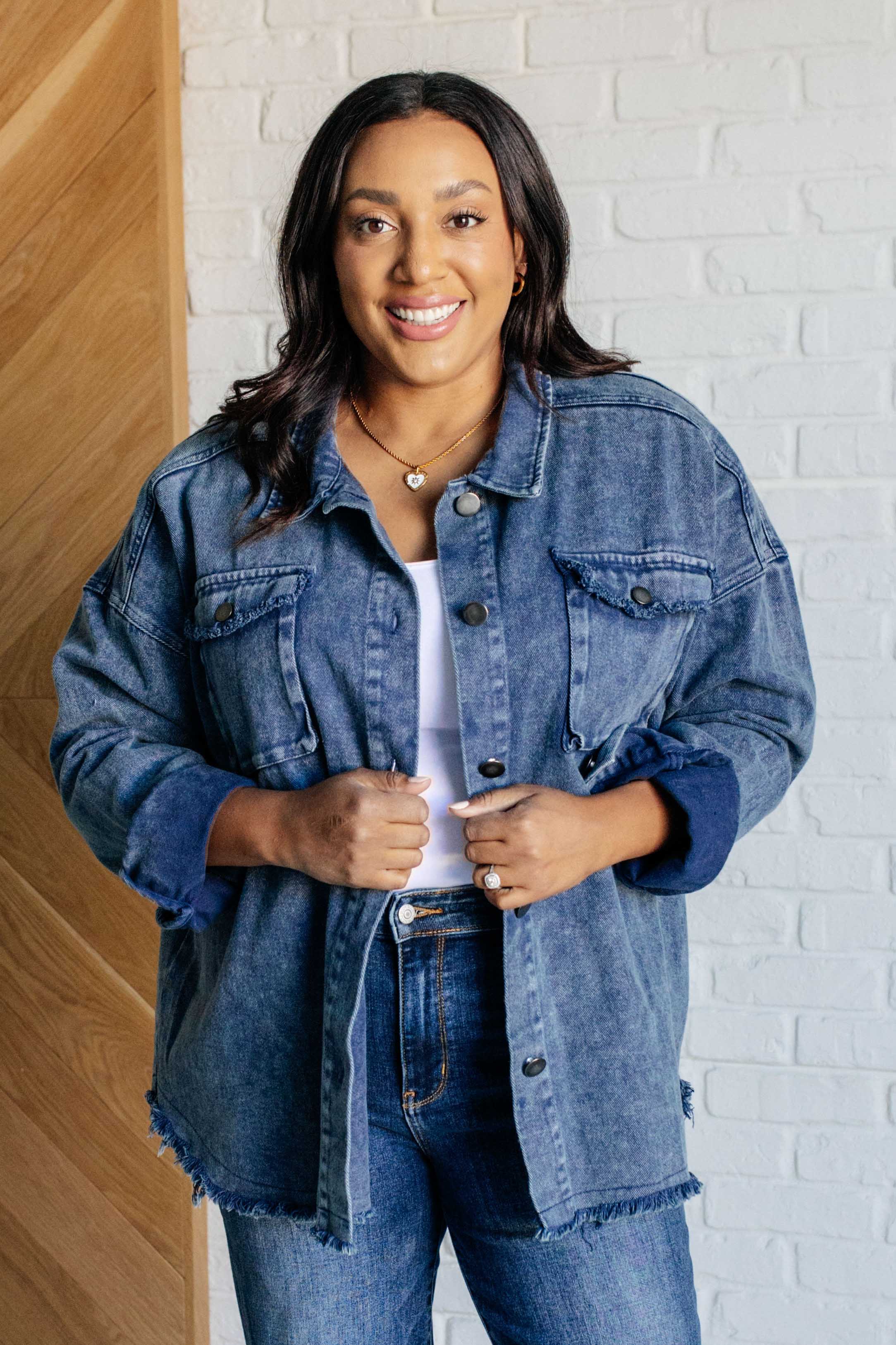 Woman smiling indoors wearing blue Just In Case Mineral Wash Shacket with buttoned chest pockets and frayed hem over white top