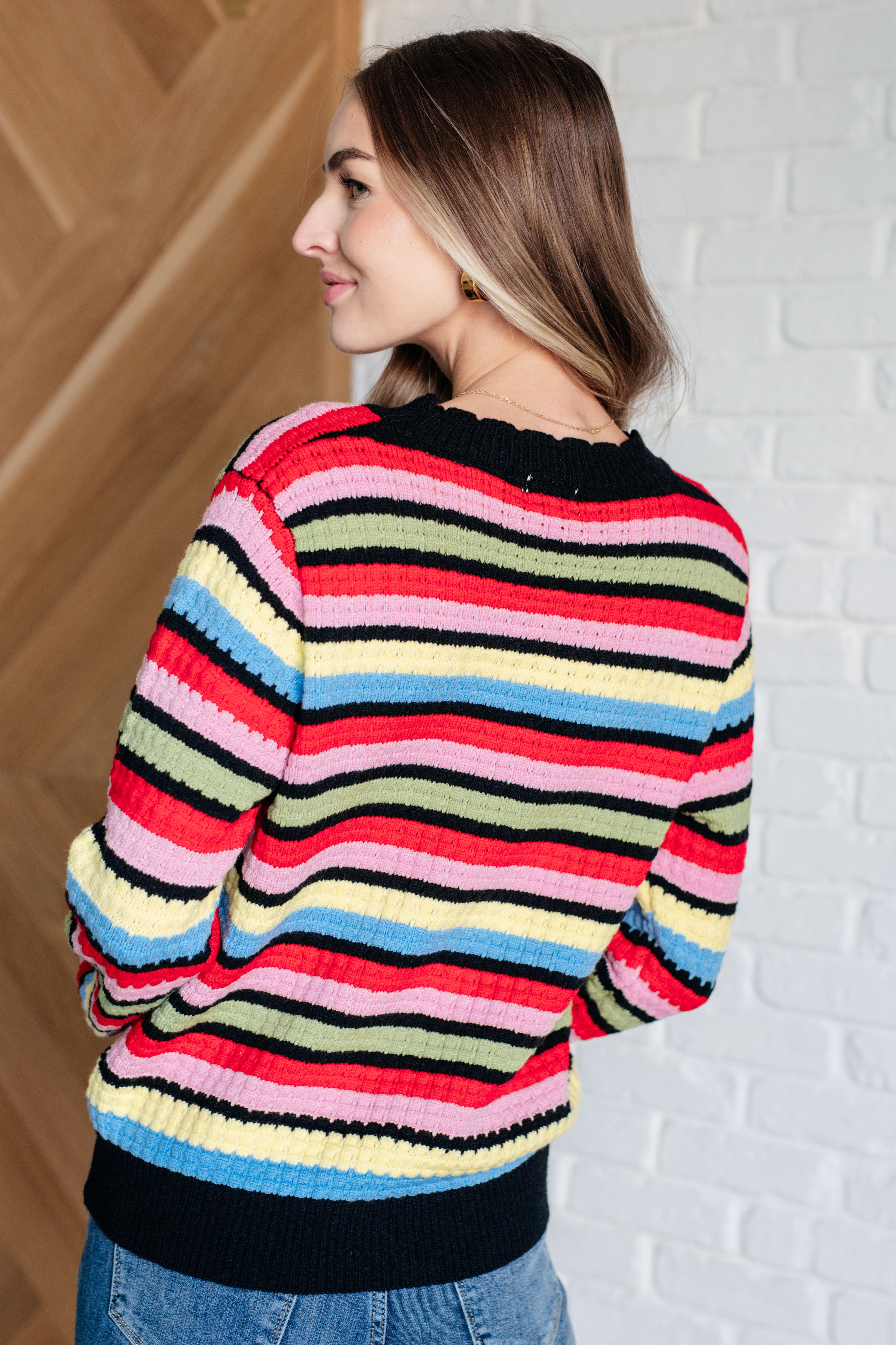 Woman indoors wearing multicolor Keep Dreaming Striped Sweater with ribbed hem and neckline viewed from back