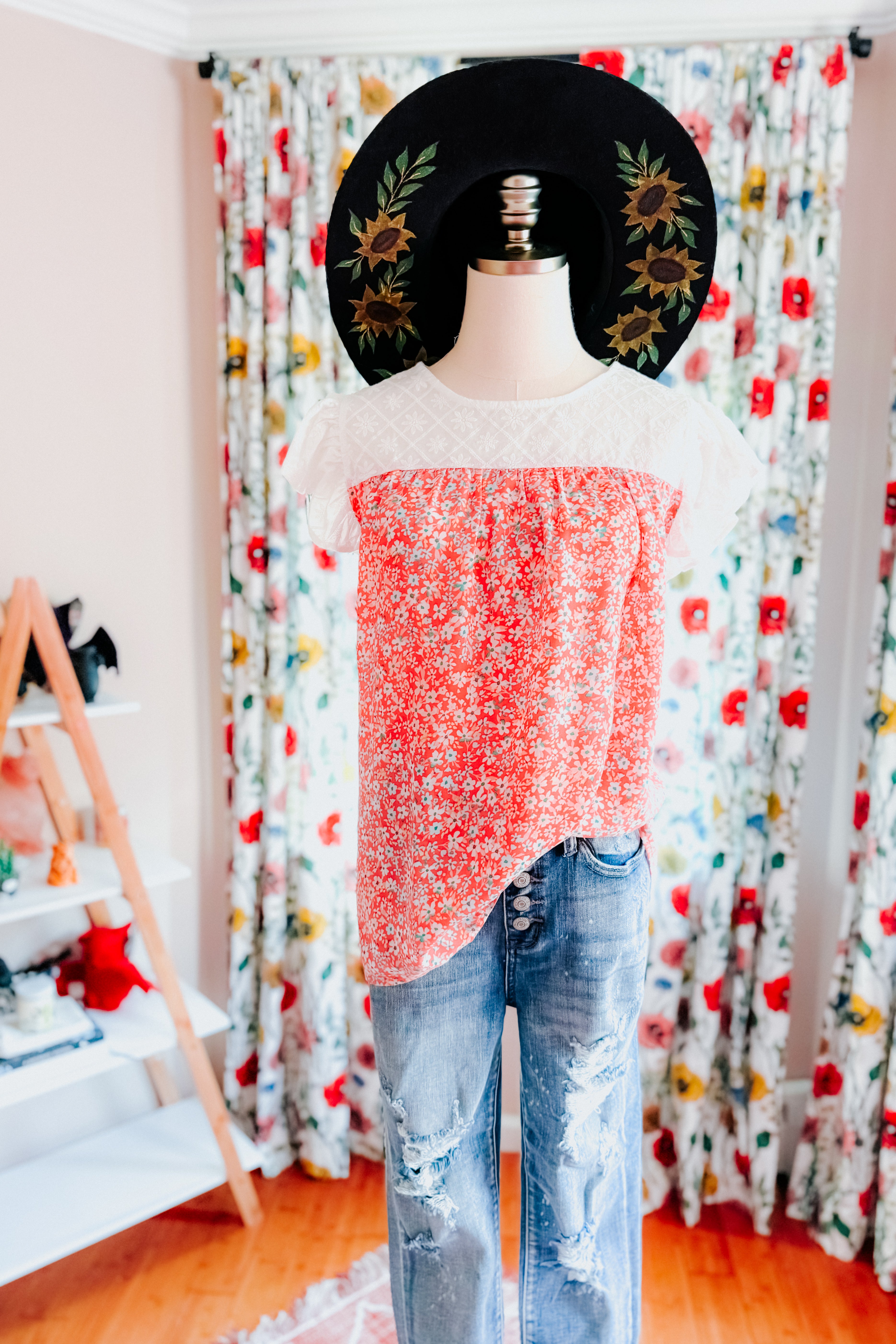 Coral floral blouse with white lace yoke paired with distressed blue jeans and black hat with sunflower embroidery