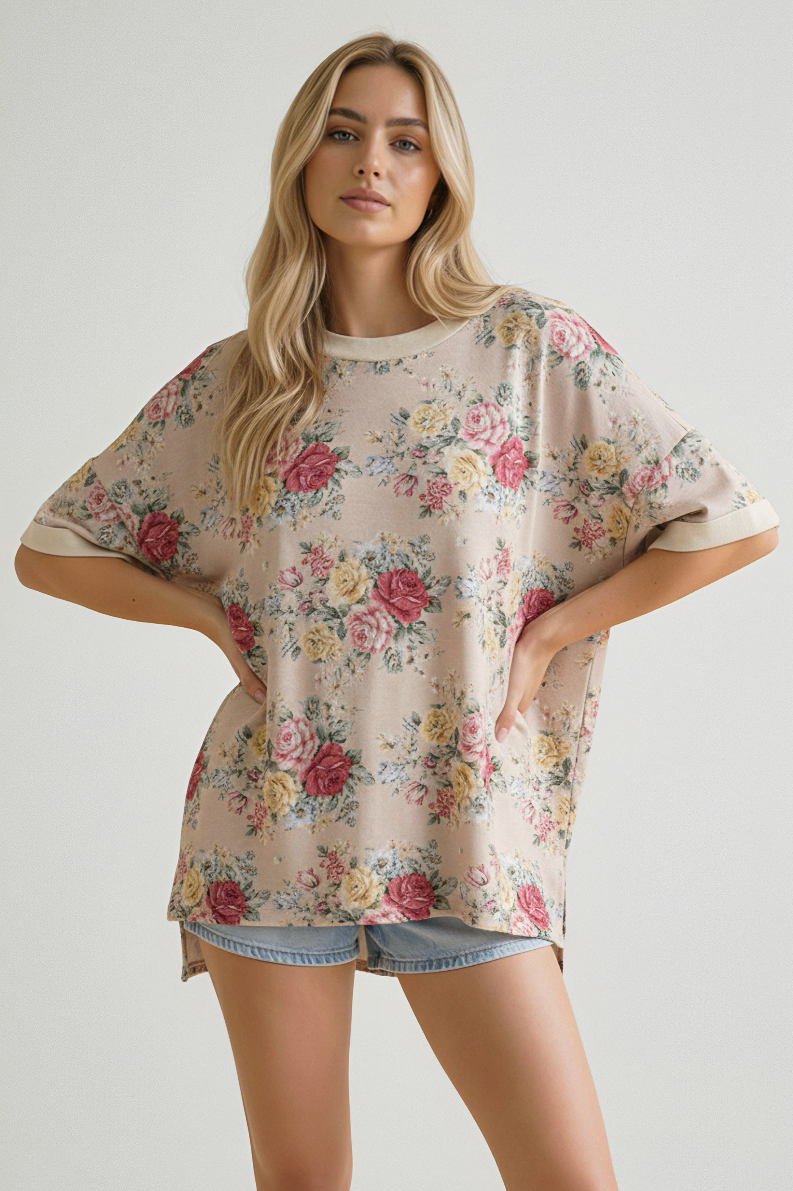 Woman wearing an oatmeal-colored floral print oversized short sleeve top paired with light denim shorts indoors