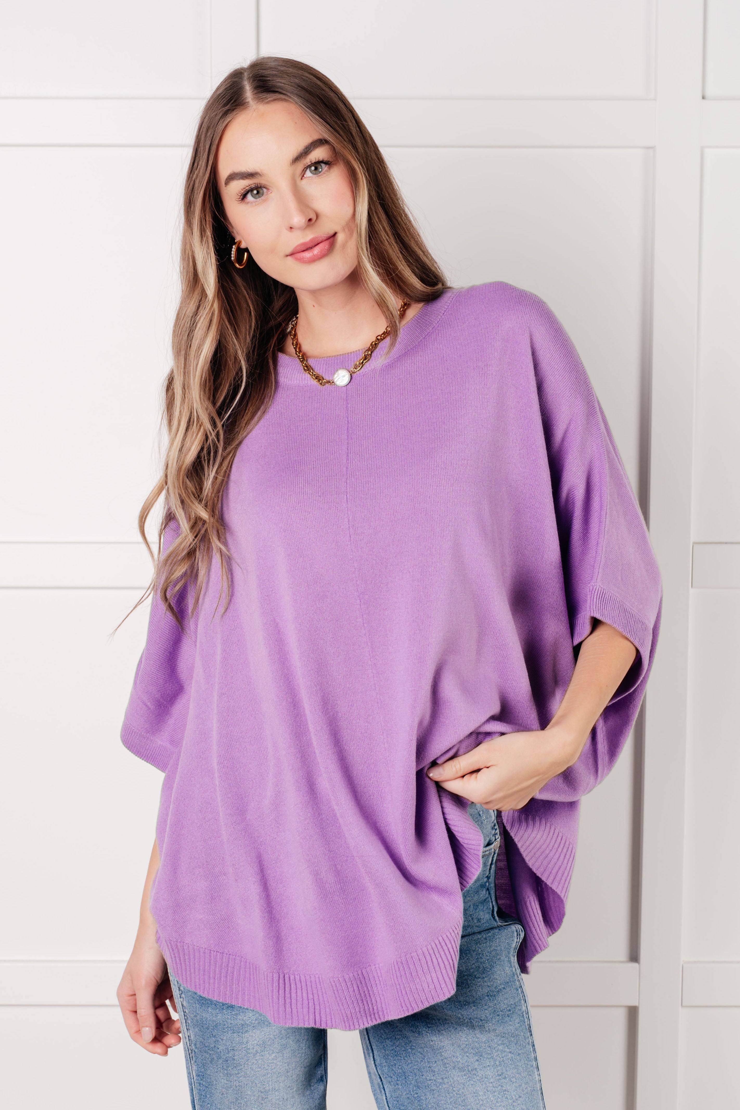 Woman wearing a relaxed lilac loose-fit top with dolman sleeves paired with light blue jeans indoors