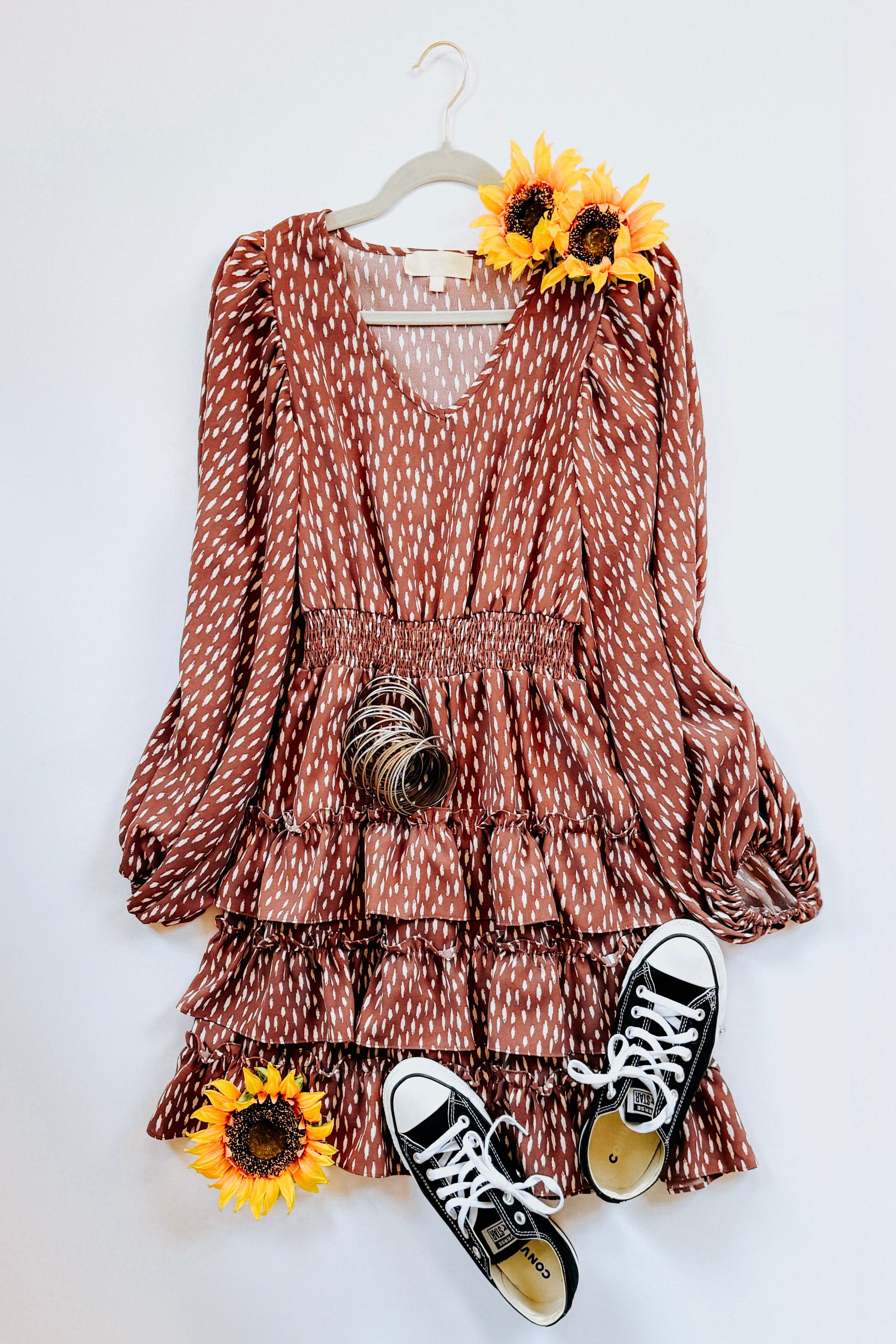 Terracotta dress with white dash pattern, puffed sleeves, smocked waist, and tiered ruffle skirt styled with black sneakers and sunflowers