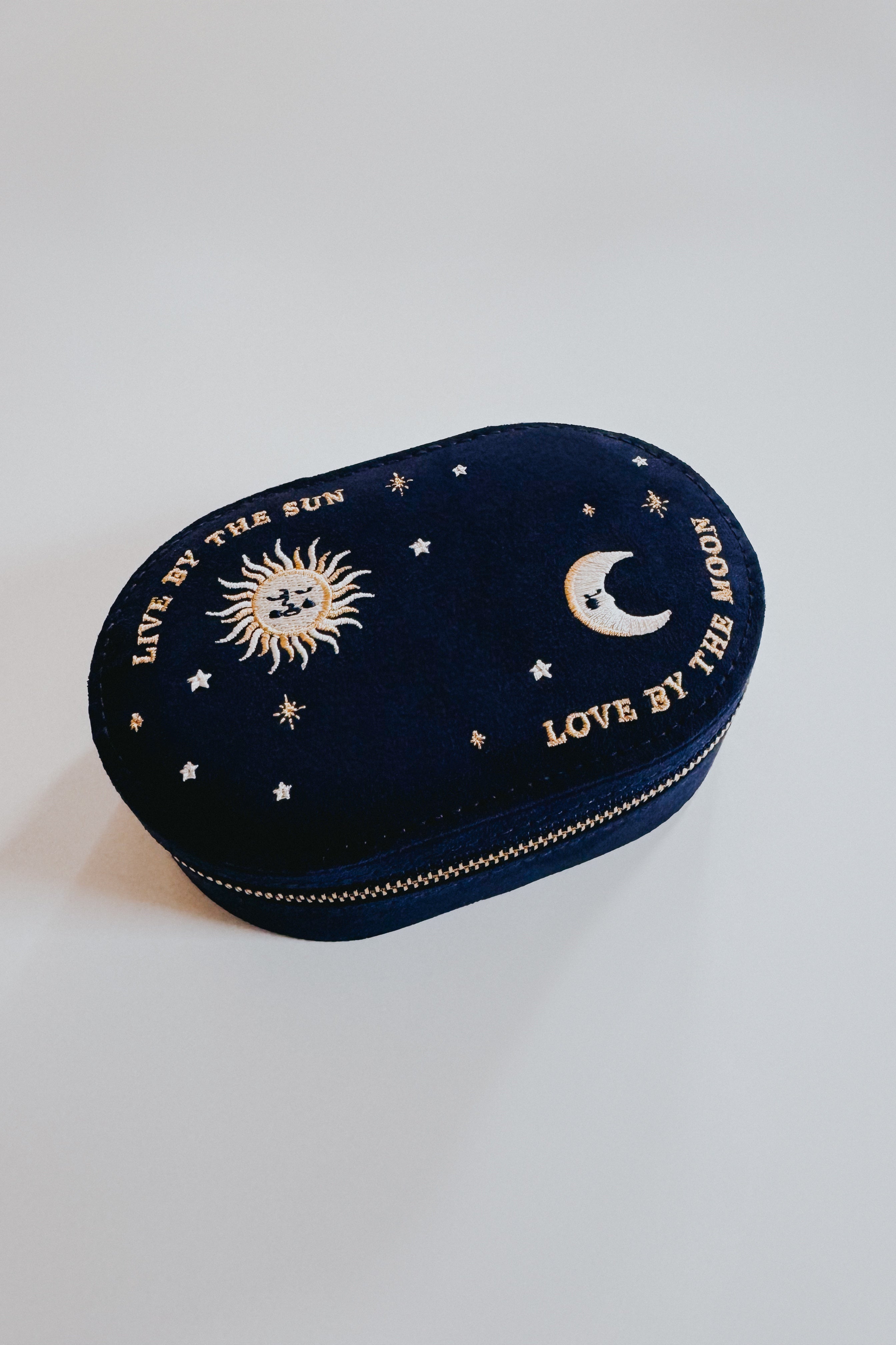 Oval navy jewelry box with embroidered sun, moon, stars, and the phrases live by the sun and love by the moon