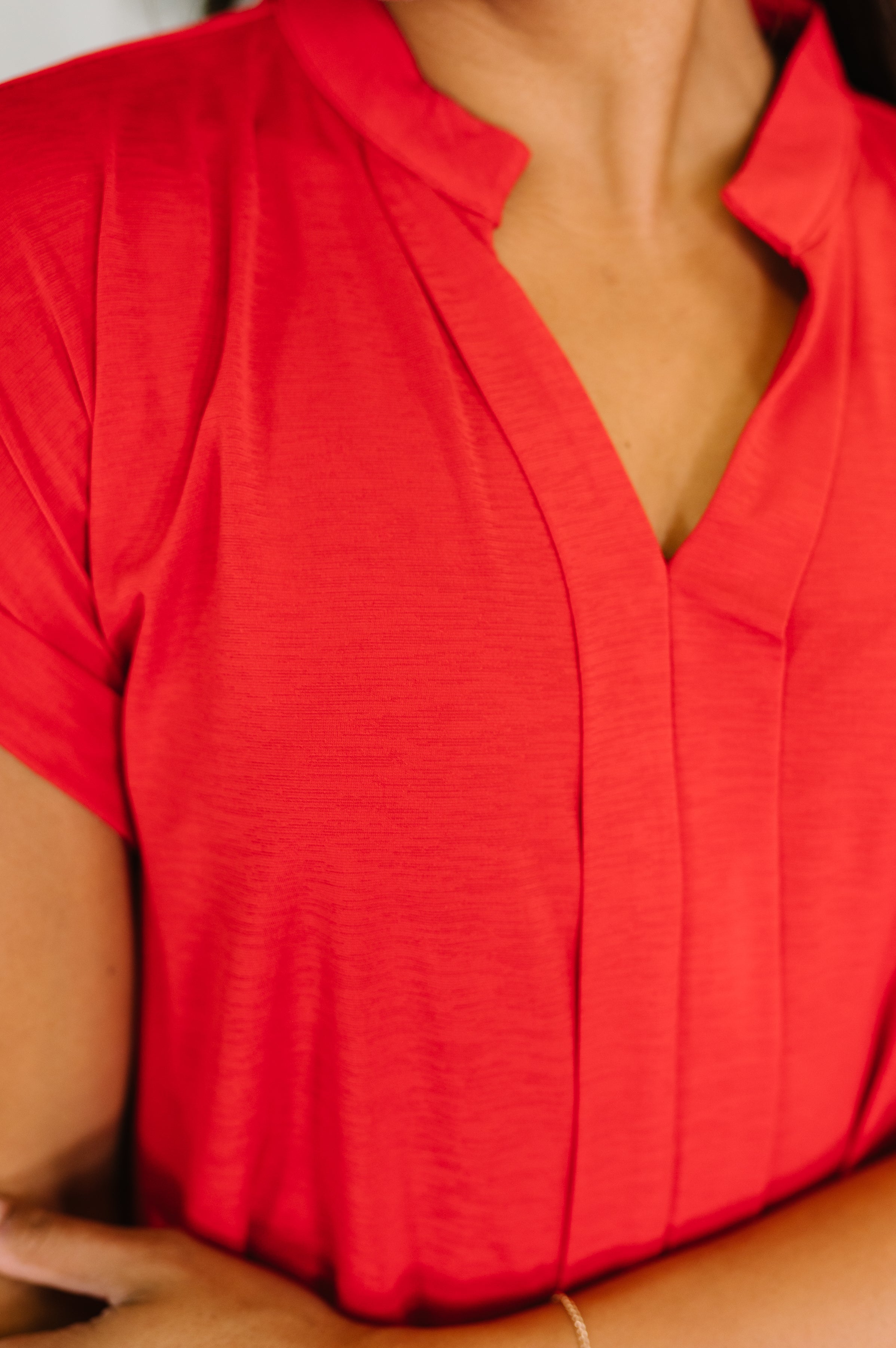 Close-up of red blouse with split neckline and soft fabric texture on relaxed fit top worn by woman
