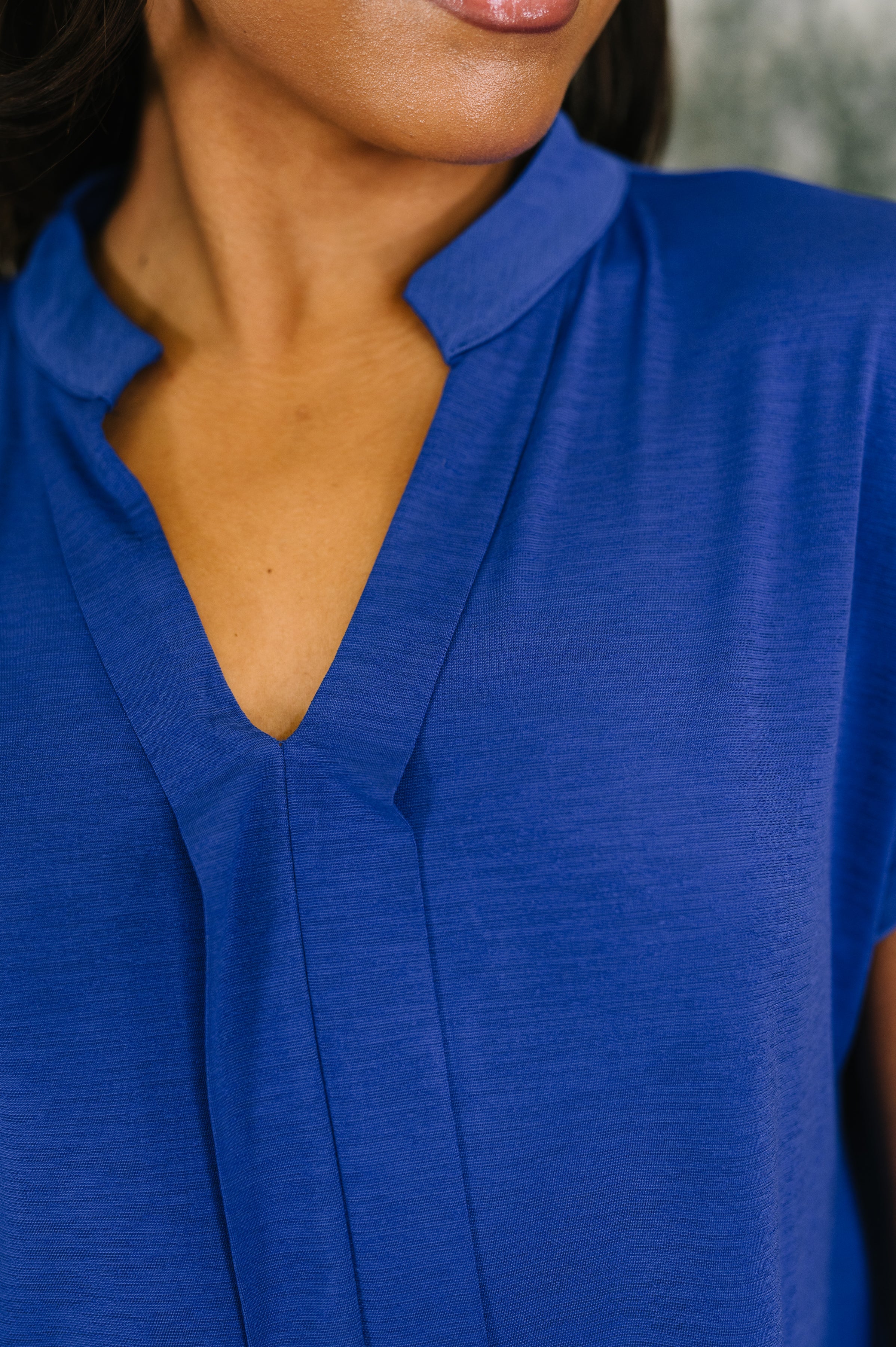 Close-up of a royal blue blouse with a split neckline showcasing smooth fabric and subtle textured detail