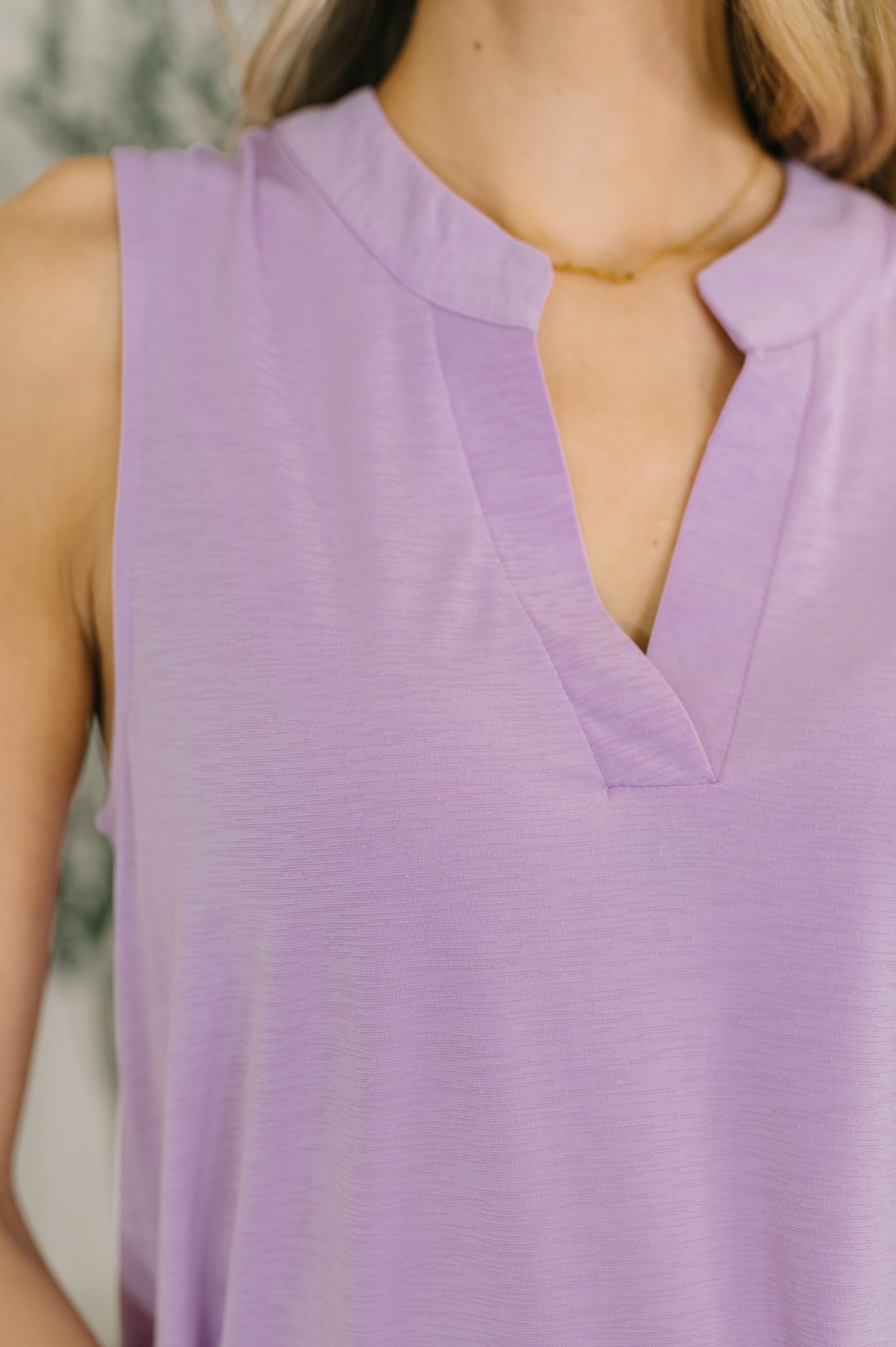 Close-up of purple sleeveless tank top with V-neckline in soft Bulgari fabric worn by model indoors