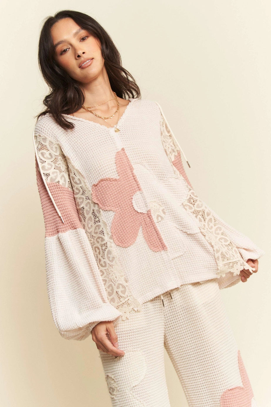 Cream waffle knit top with pink floral and lace panel details worn by woman with dark hair
