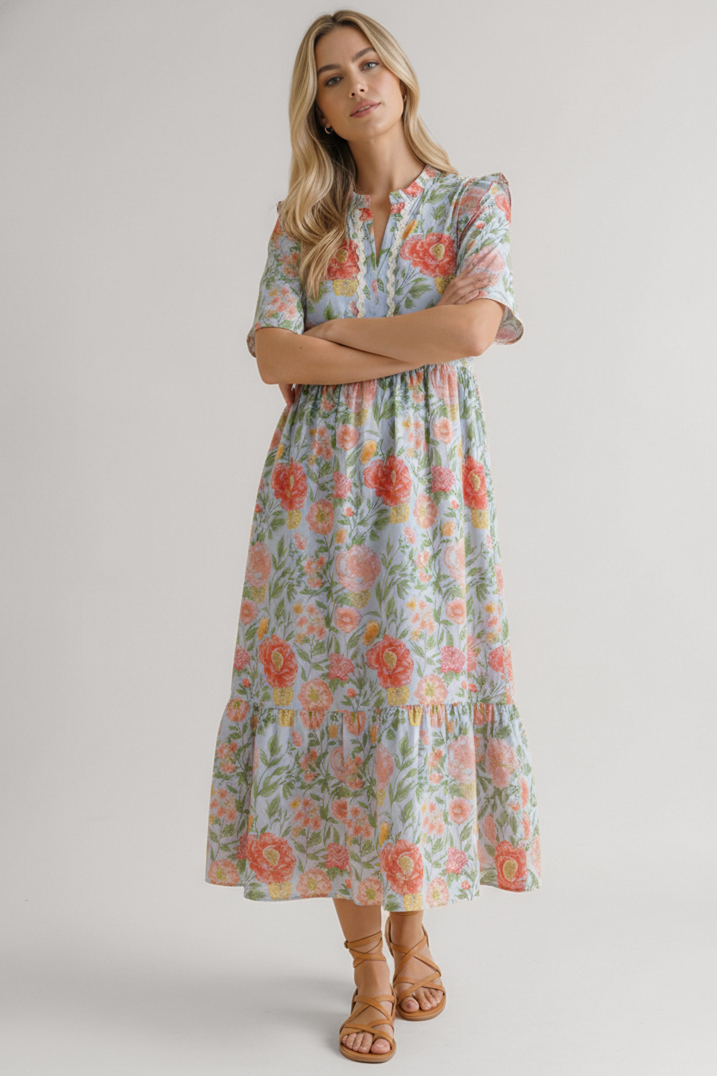 Woman wearing sky blue floral midi dress with half sleeves and tiered skirt standing with arms crossed