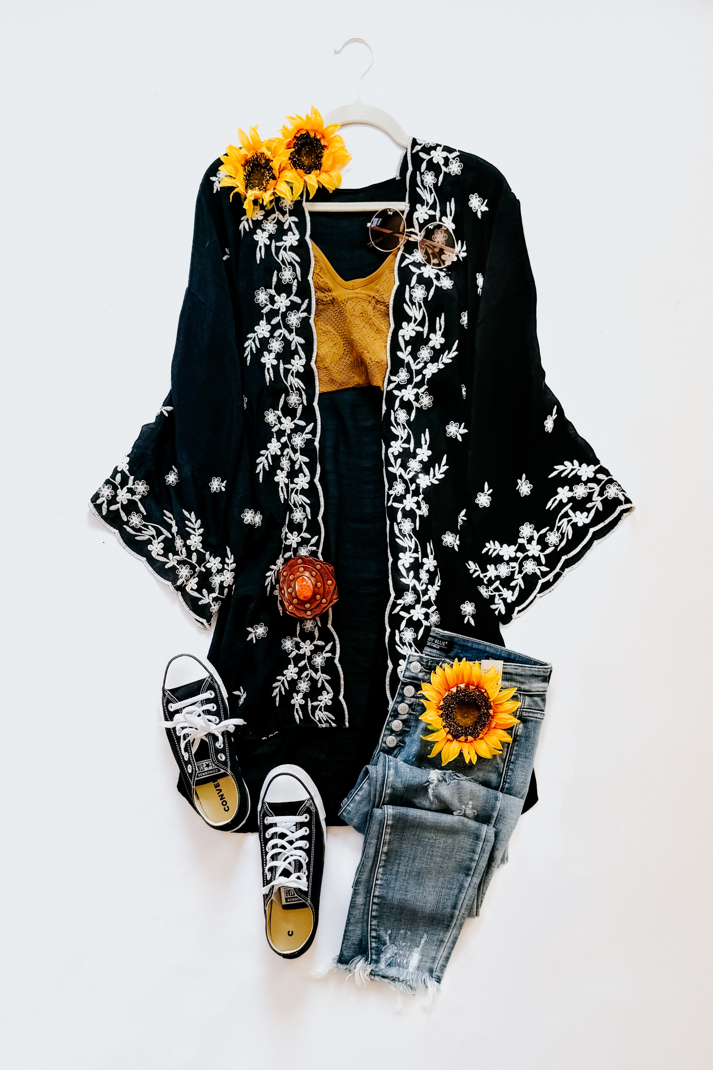 Black floral embroidered duster layered over mustard knit top paired with distressed light blue jeans and black sneakers