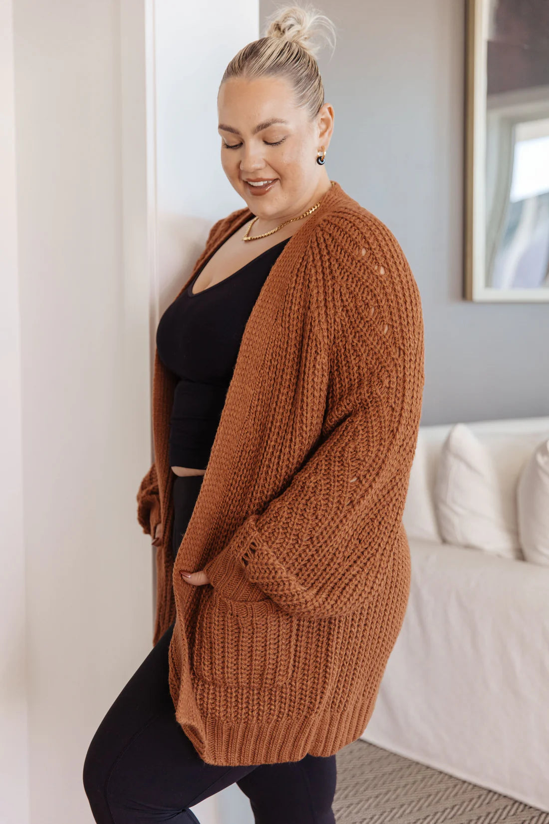 Plus-size woman wearing a chestnut oversized knit cardigan with balloon sleeves and front pockets indoors