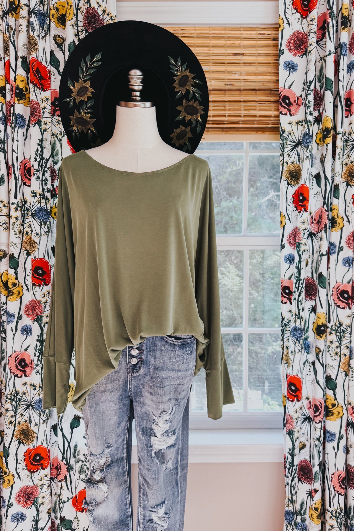 Green brushed microfiber top with a boat neckline and relaxed dolman sleeves styled on a mannequin with distressed jeans and a black hat
