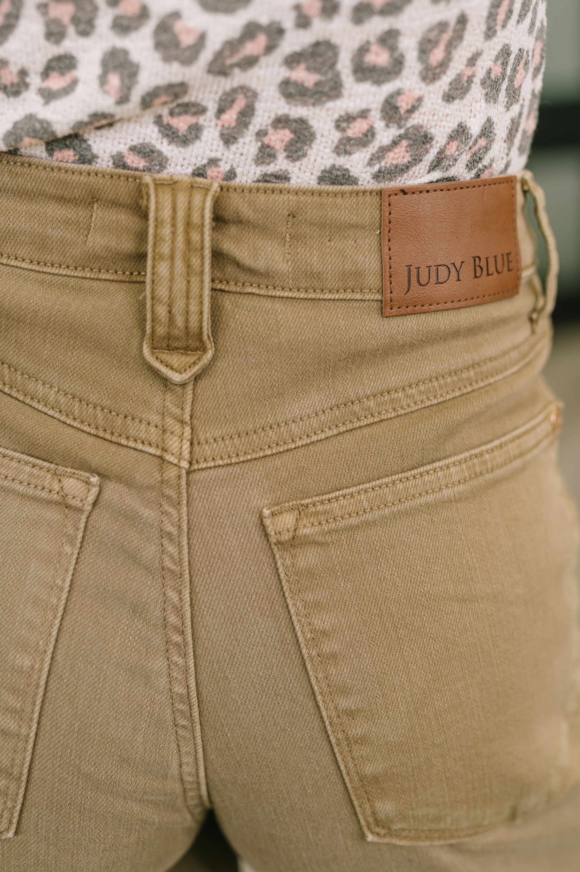 Close-up of high-rise brown wide-leg jeans featuring vintage front yoke and leather Judy Blue patch with leopard print top
