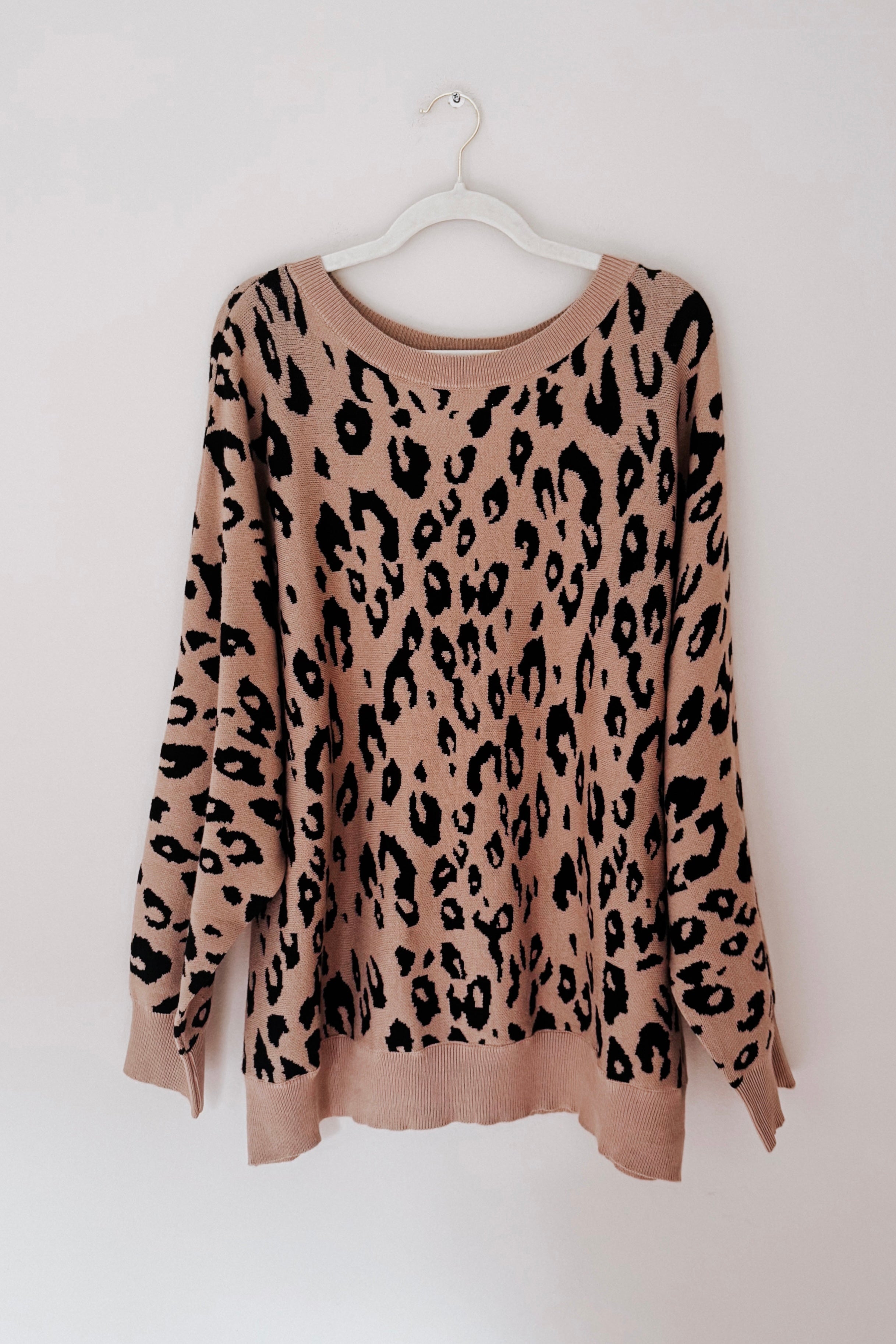 Mocha sweater with an oversized fit featuring a bold black leopard pattern, displayed on a white hanger against a neutral background.
