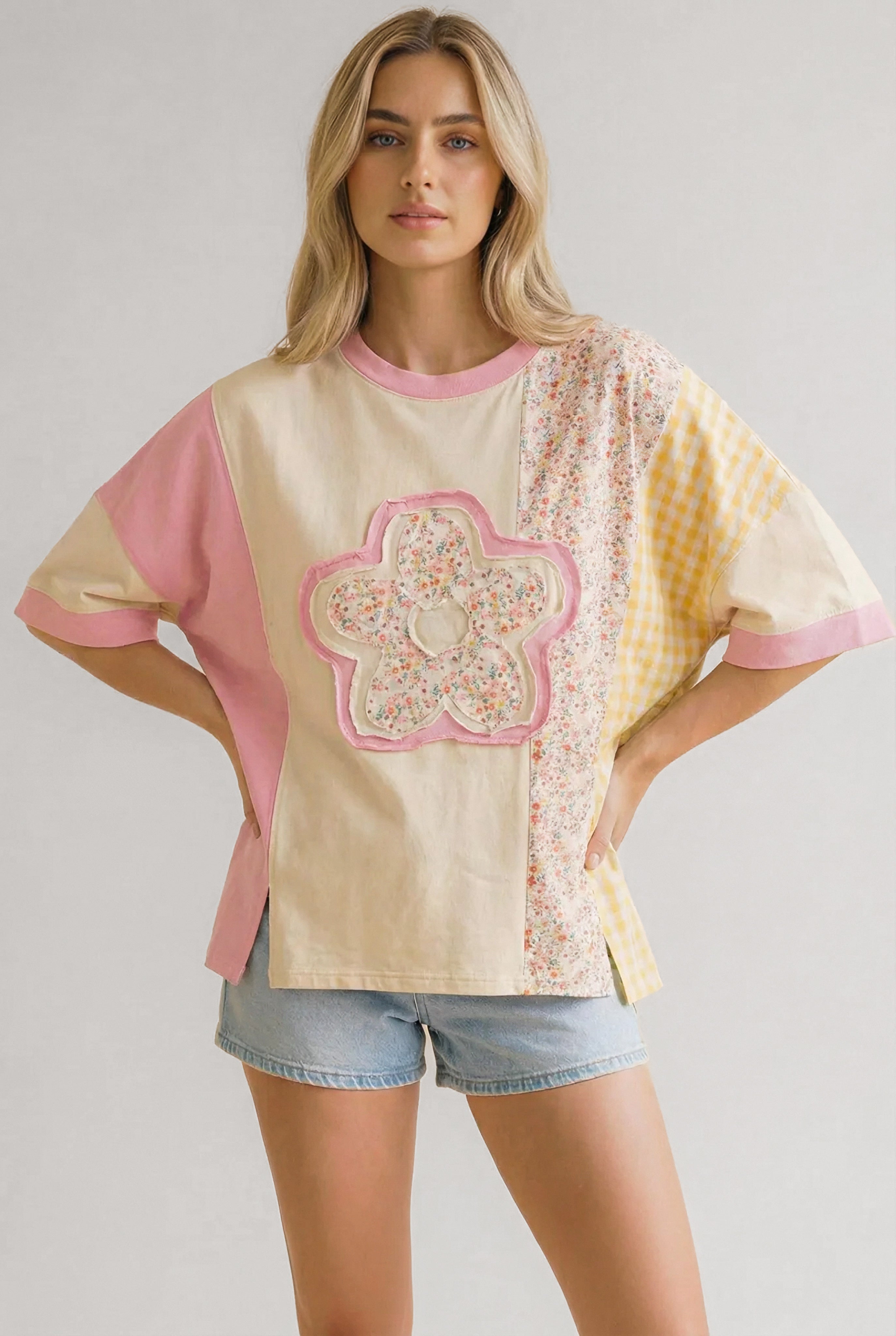 Woman wearing a relaxed patchwork tee with floral and gingham patterns paired with denim shorts indoors