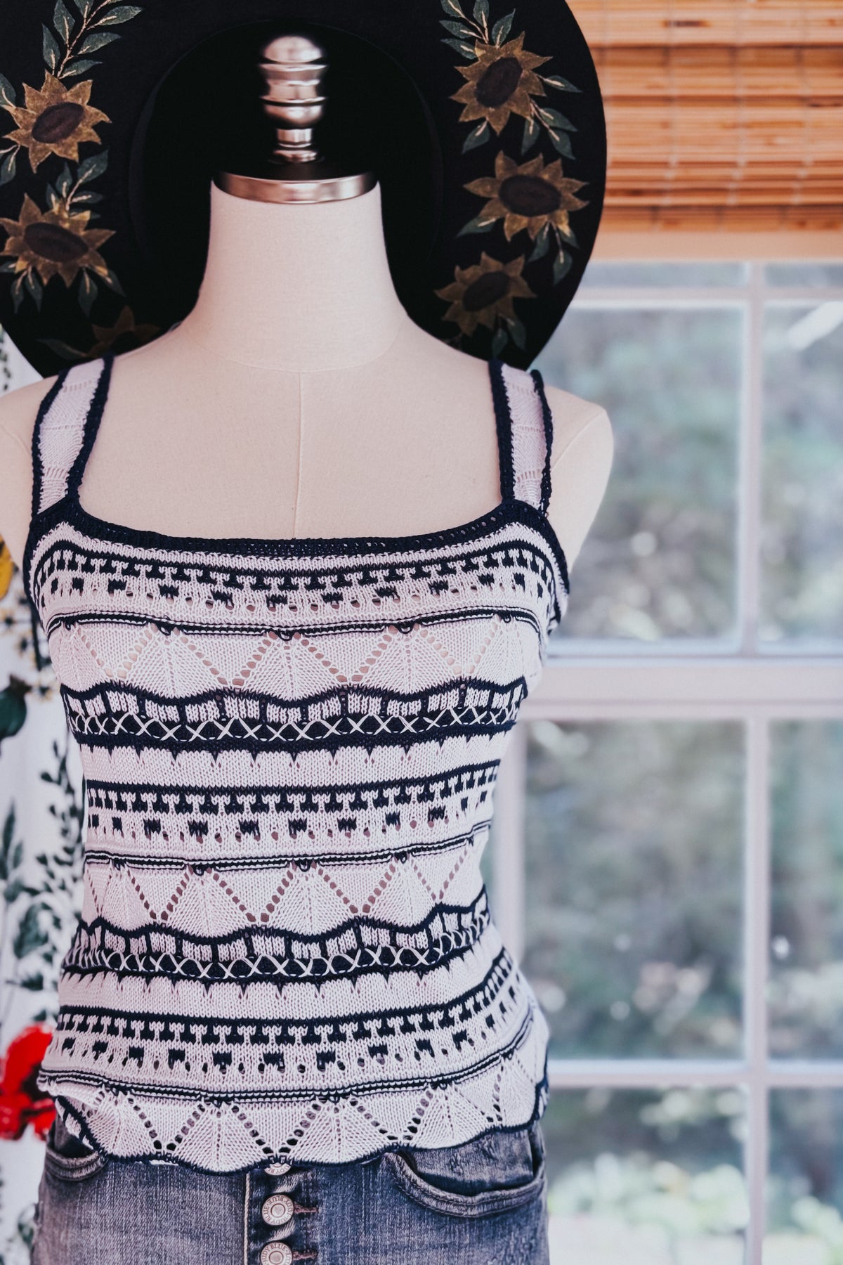 Blue pointelle knit sweater tank with scalloped trim and contrasting patterned stripes displayed on a mannequin indoors