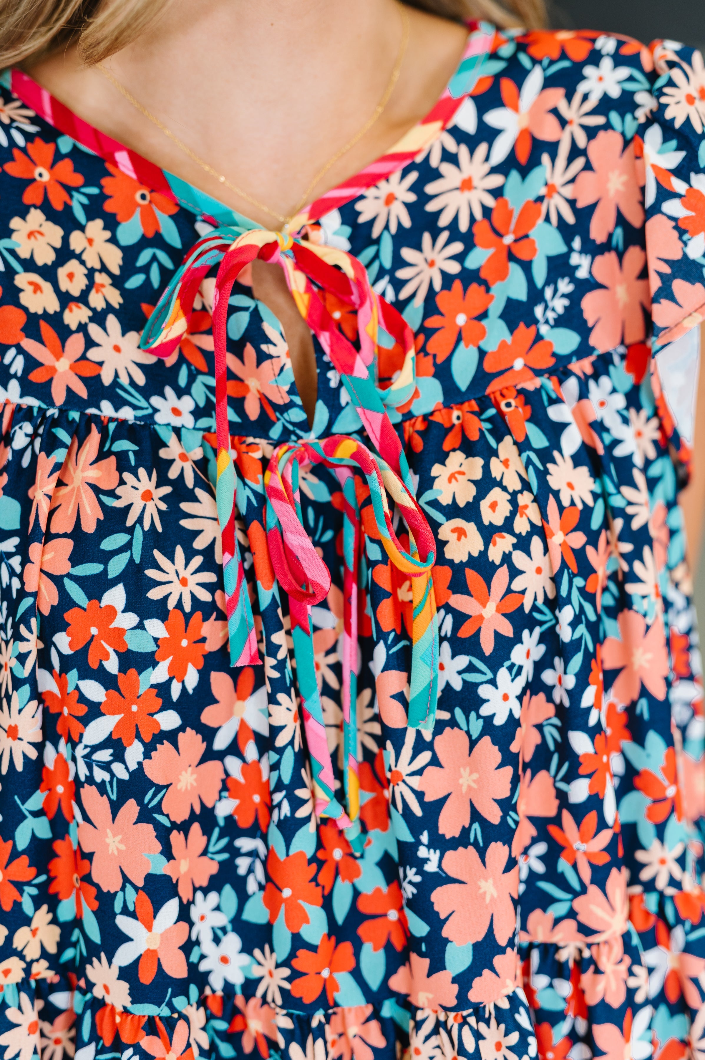 Close-up of a navy floral dress with flutter sleeves and a neck tie showcasing eclectic, size-inclusive style.