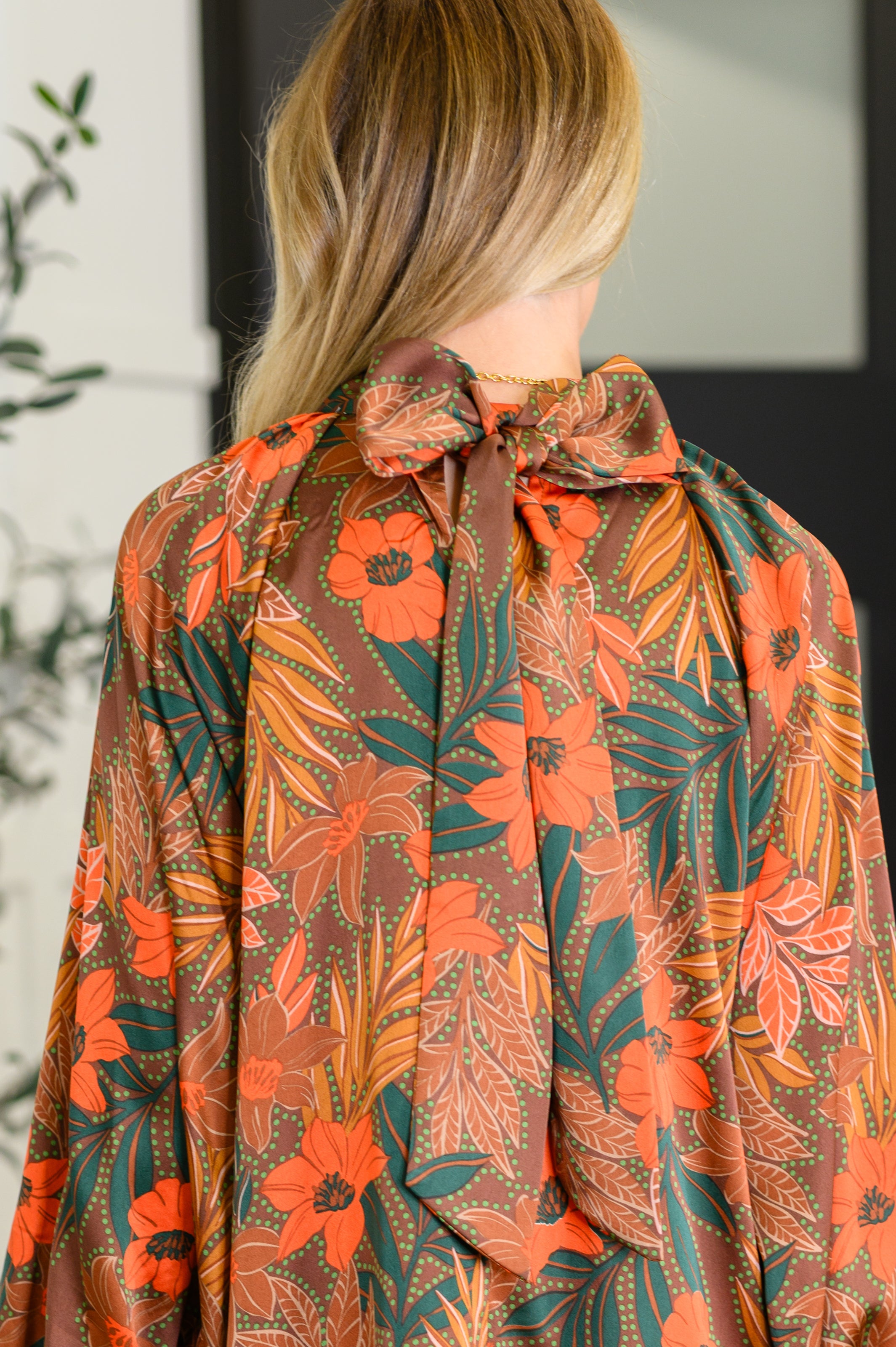 Back view of rust floral balloon sleeve dress with large tied bow neckline in eclectic, free-spirited style