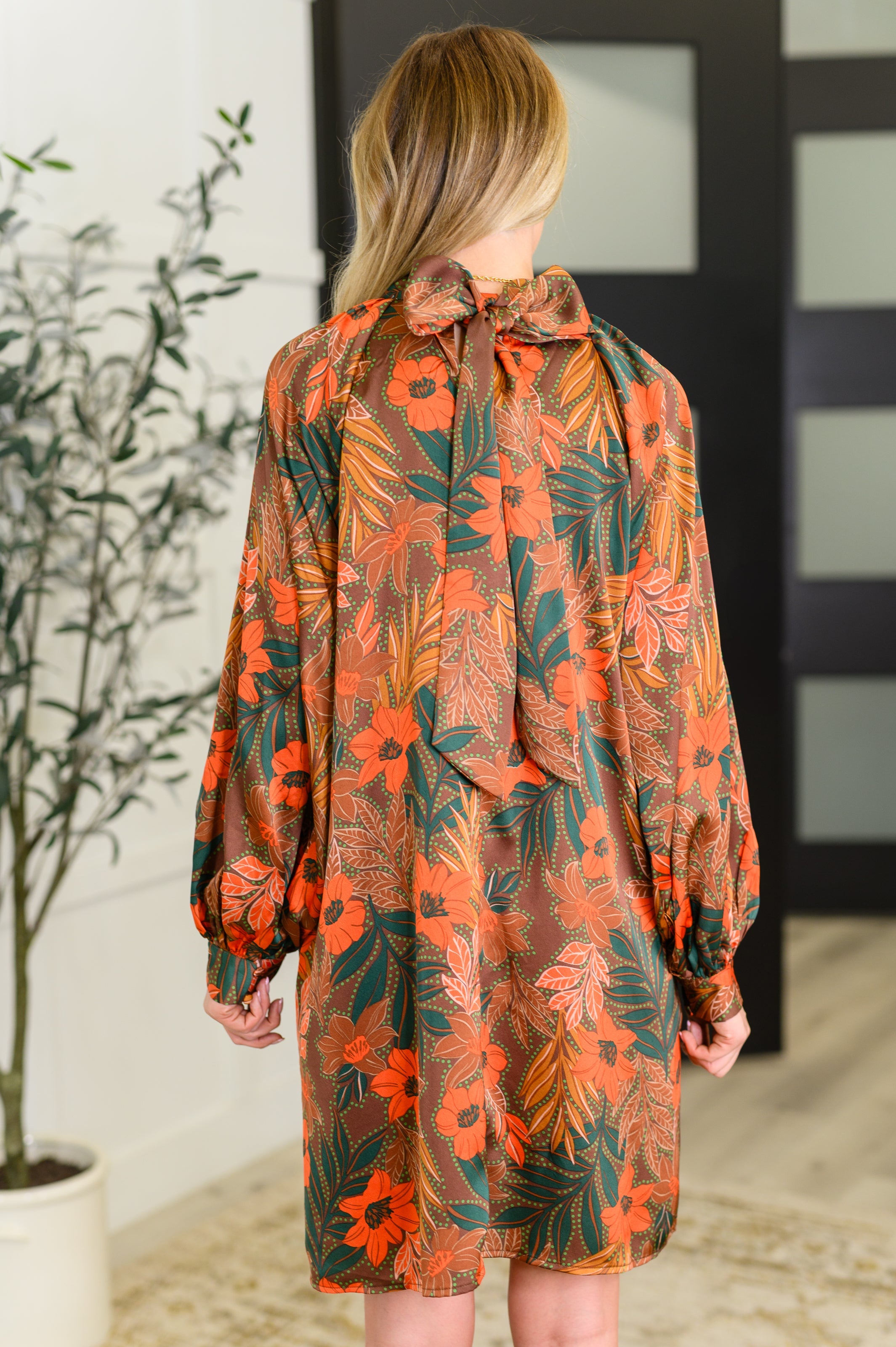 Back view of rust floral balloon sleeve dress with tied bow neckline in eclectic, free-spirited style