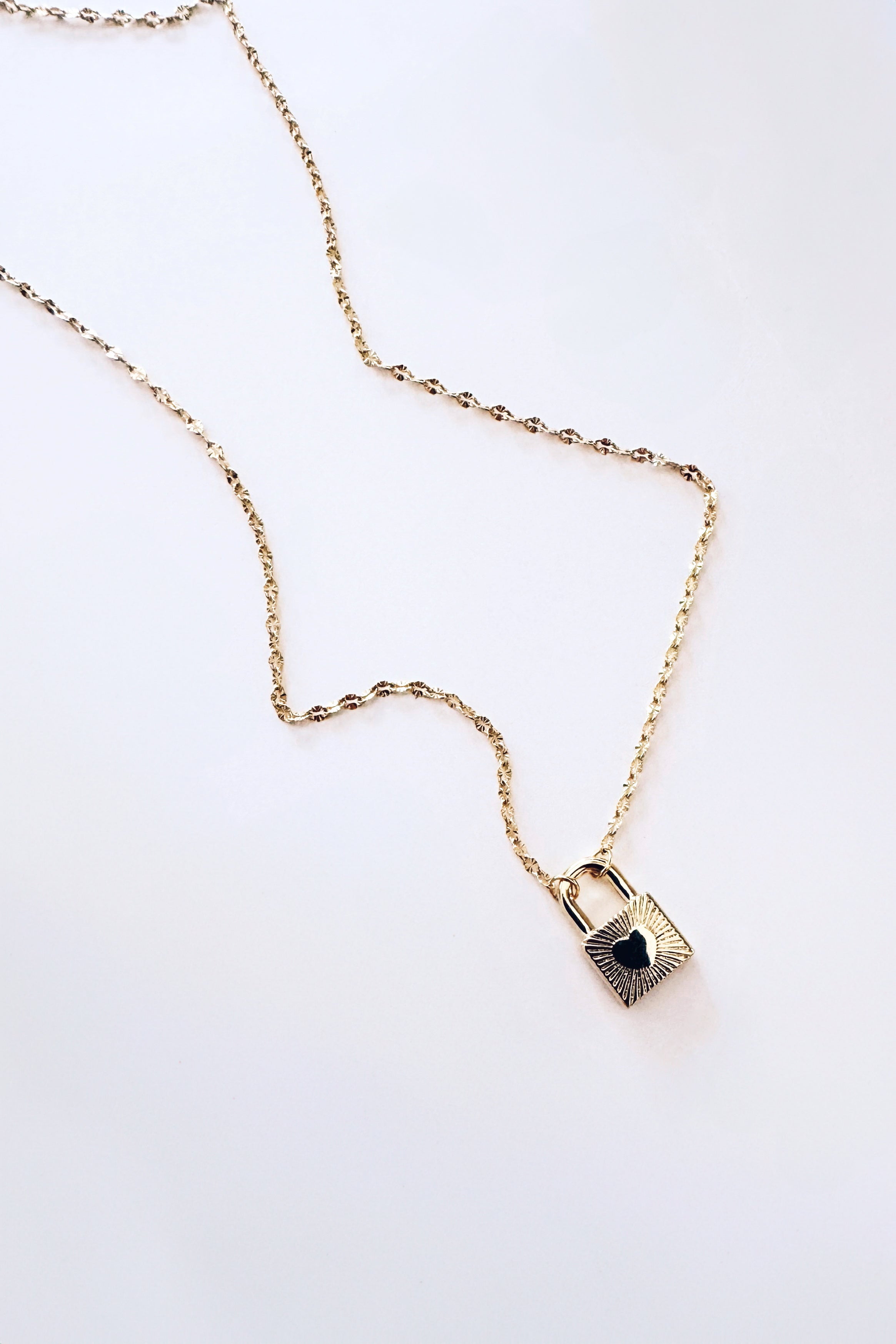 Gold chain with textured links and a love locked pendant featuring a heart in eclectic, free-spirited style