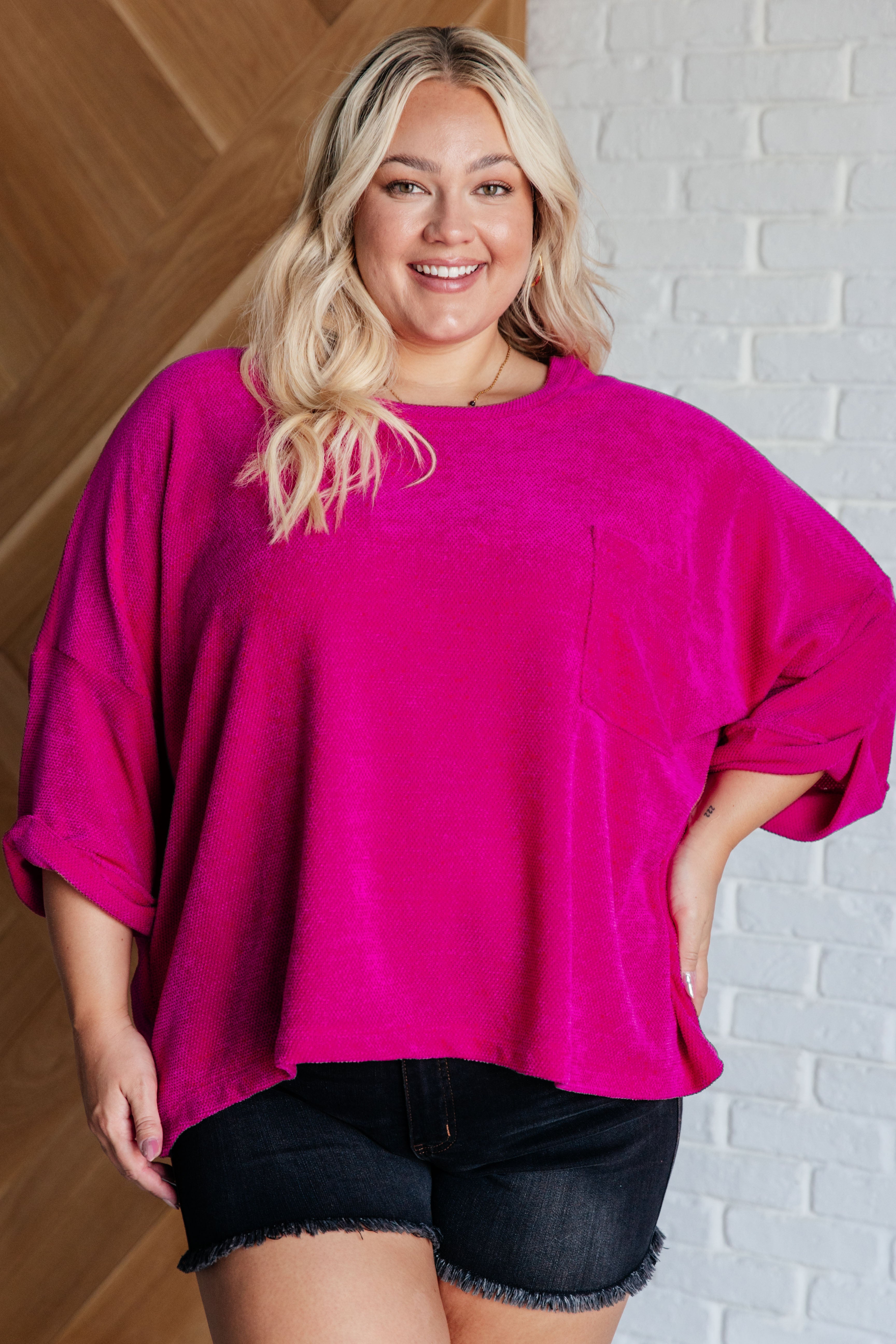 Plus-size model wearing fuchsia chenille blouse with rolled sleeves and front pocket in eclectic, free-spirited style