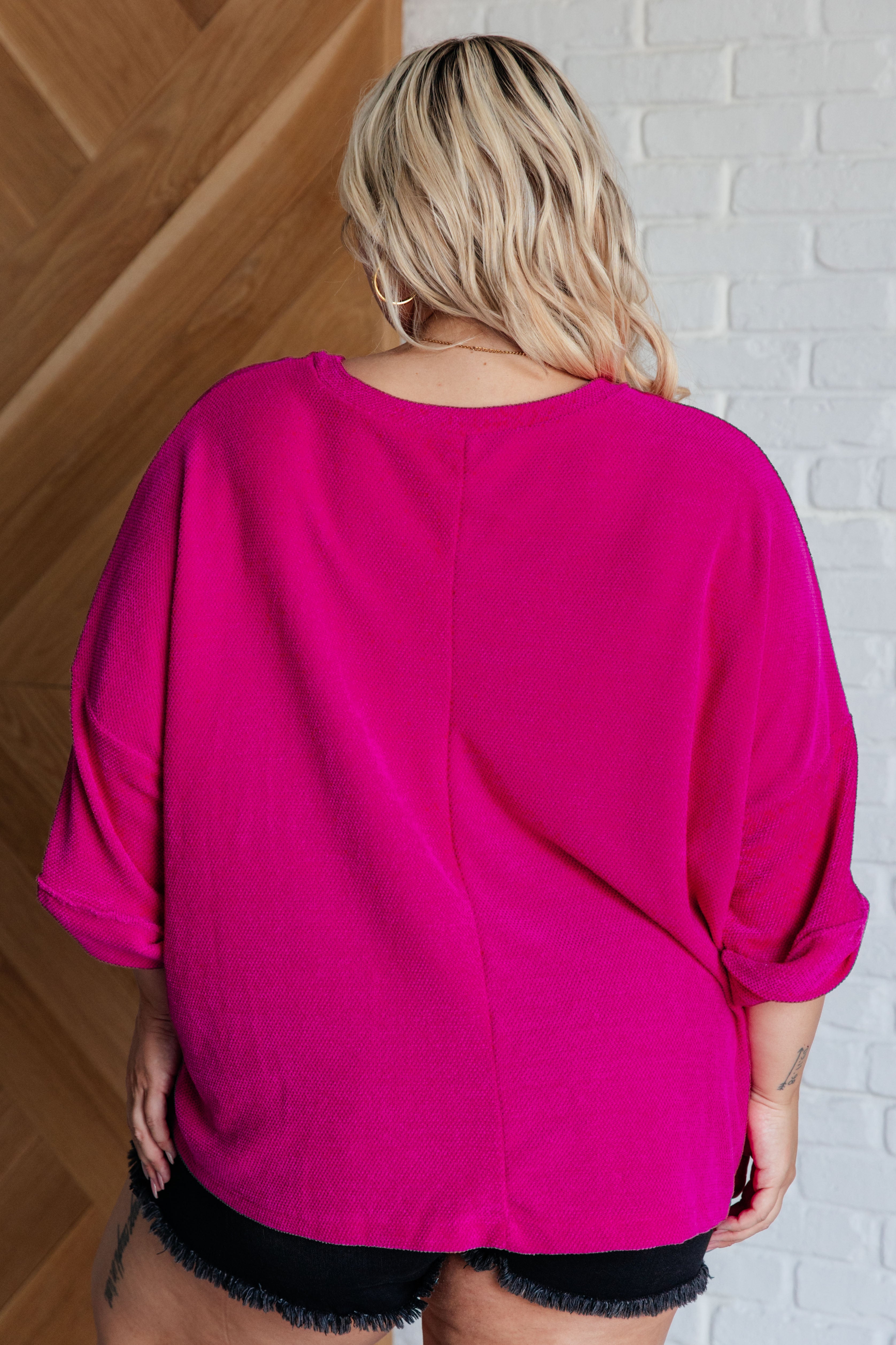 Back view of woman wearing oversized fuchsia chenille blouse with rolled sleeves and relaxed fit in eclectic style