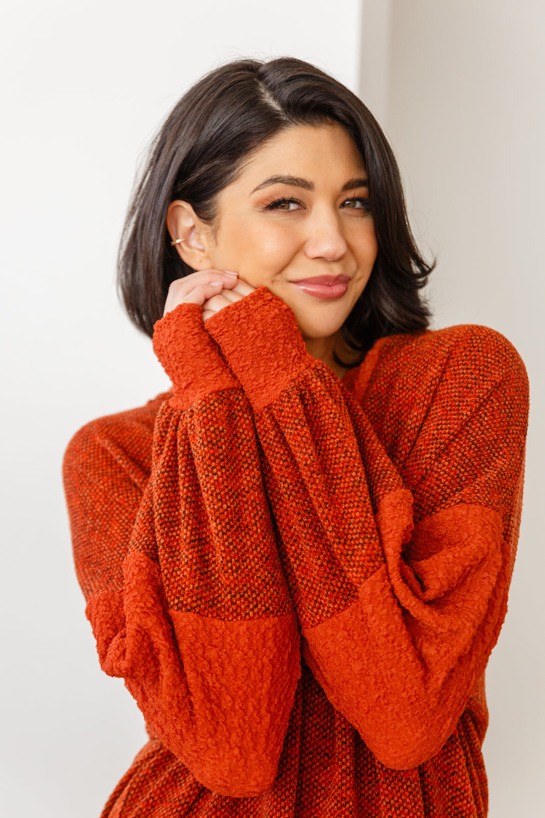 Woman in rust color block hoodie with textured knit fabric and oversized sleeves in eclectic, size-inclusive style