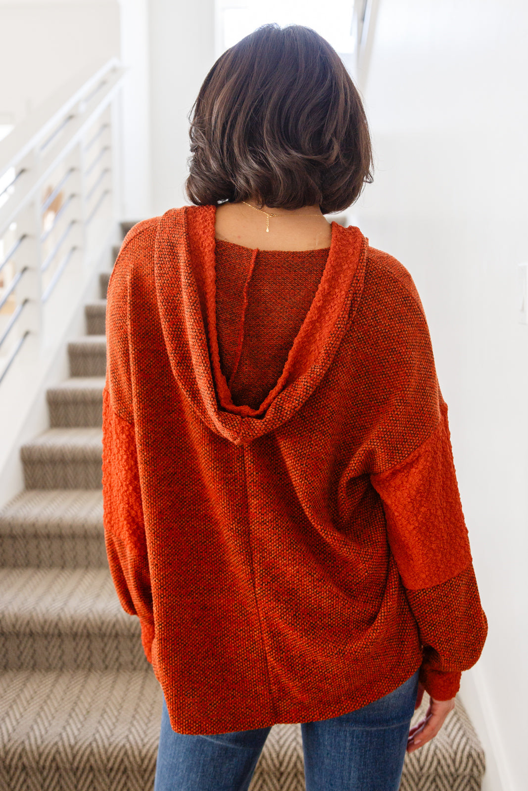 Woman in rust color block hoodie with textured knit fabric and hood in relaxed, eclectic style