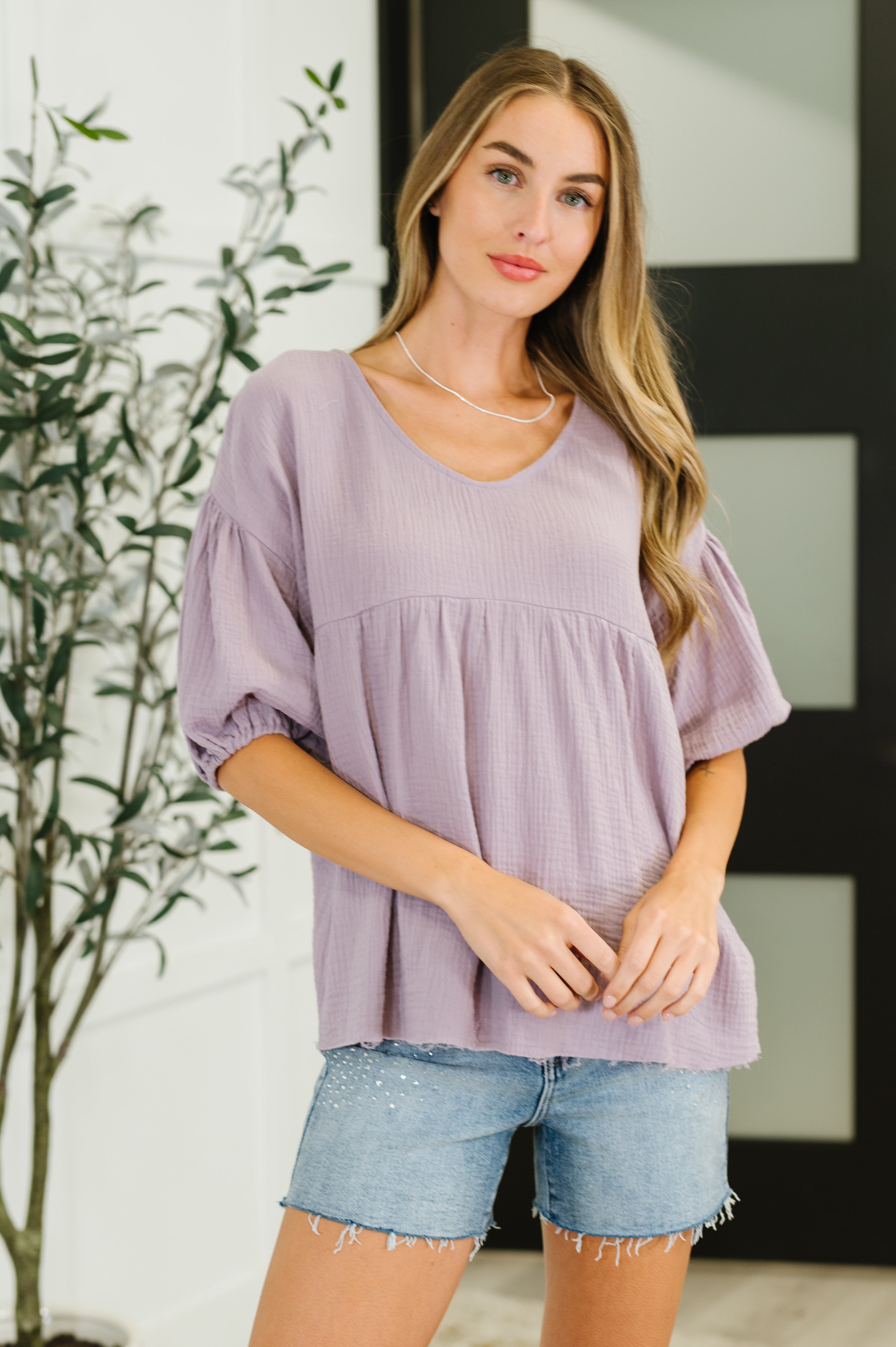 Woman wearing lavender bubble sleeve peasant blouse with relaxed fit and textured fabric in eclectic, free-spirited style