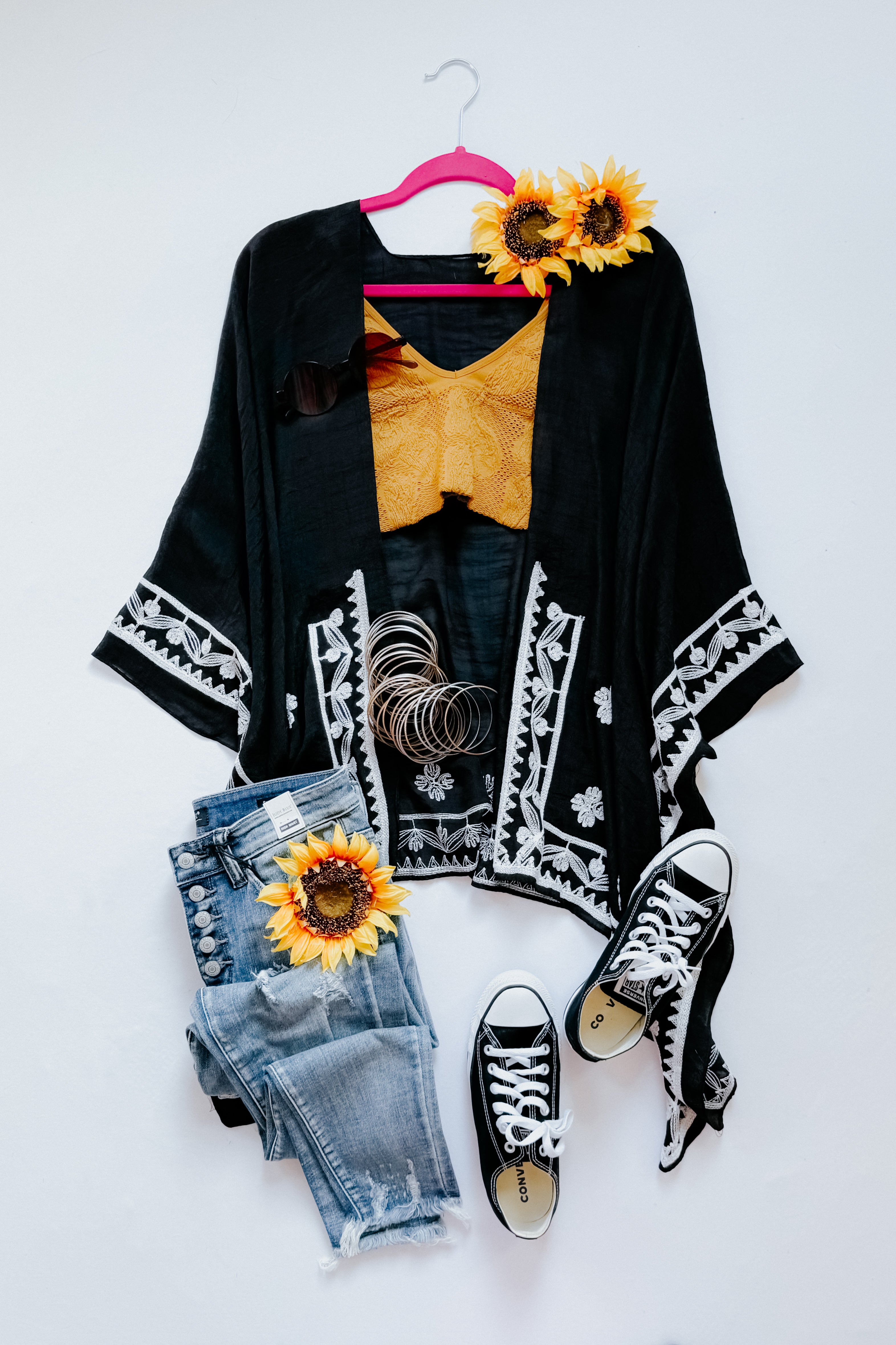 Black embroidered layering piece with white floral trim styled with mustard top, denim jeans, and black sneakers in bold look