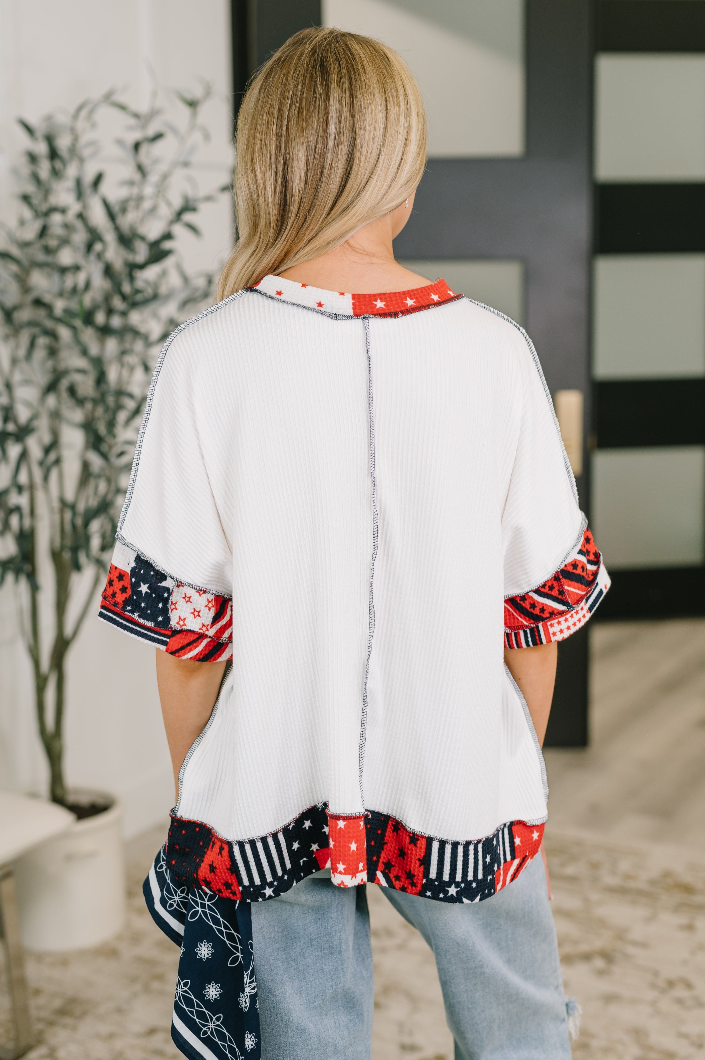 Back view of cream cable ribbed top with red, white, and navy patchwork details and dolman sleeves in eclectic style