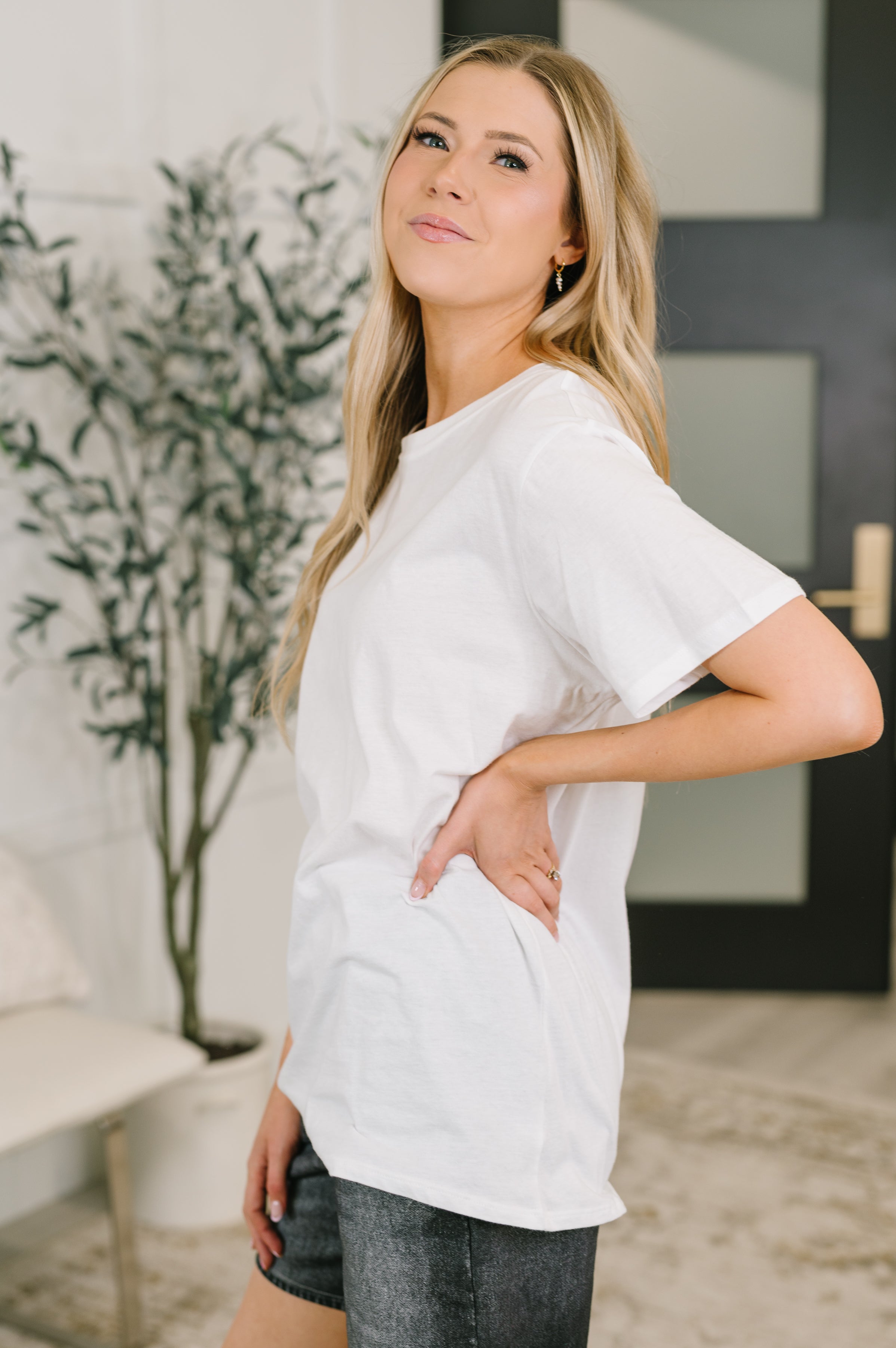 Woman wearing white relaxed fit tee with short sleeves paired with dark casual shorts in cozy indoor space
