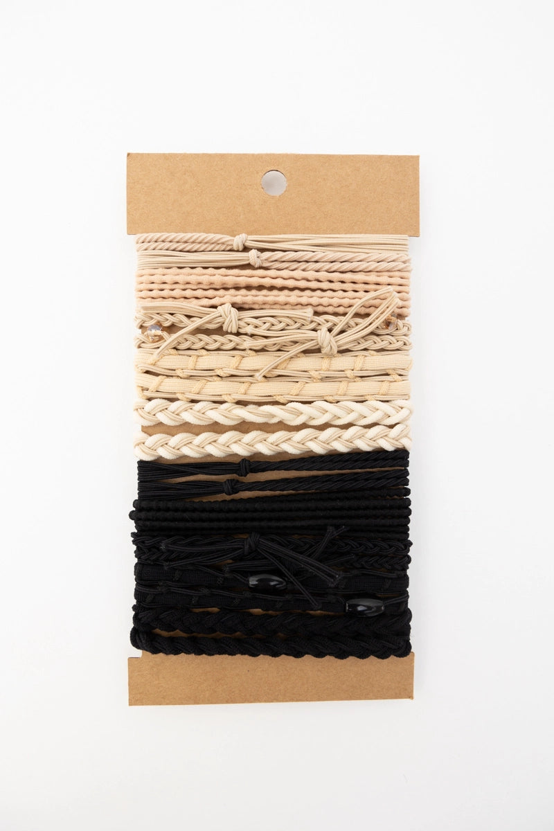 Set of cream and black textured stackable hair tie bracelets on natural brown card backing