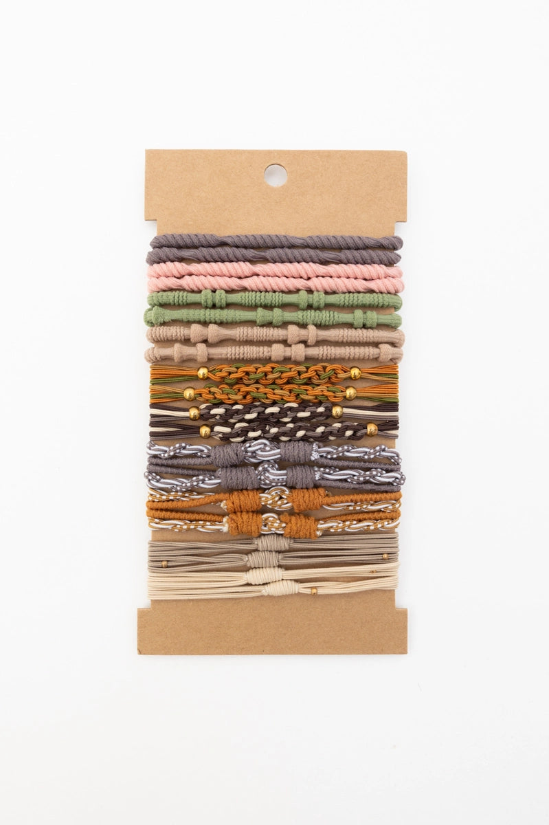Set of earth tone stackable hair tie bracelets featuring braided and knotted designs on neutral backing card