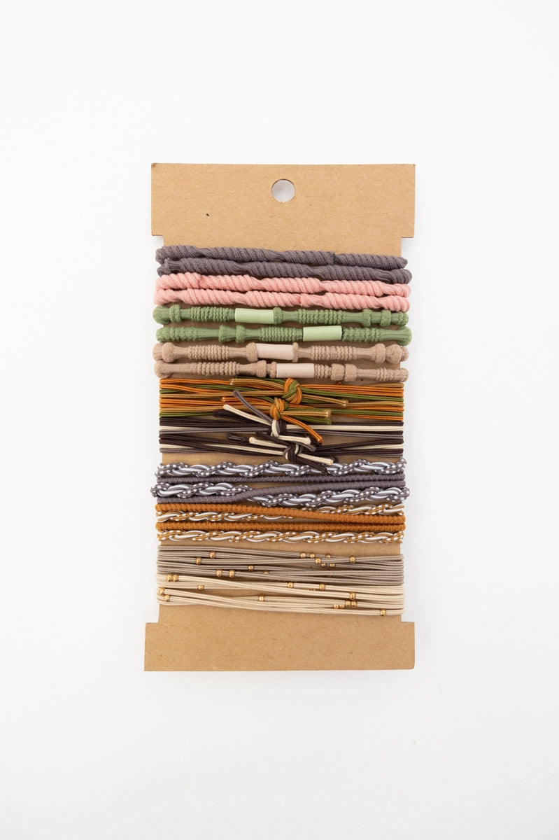 Set of earth tone stackable hair tie bracelets with varied textures and subtle knot and bead details on kraft card backing