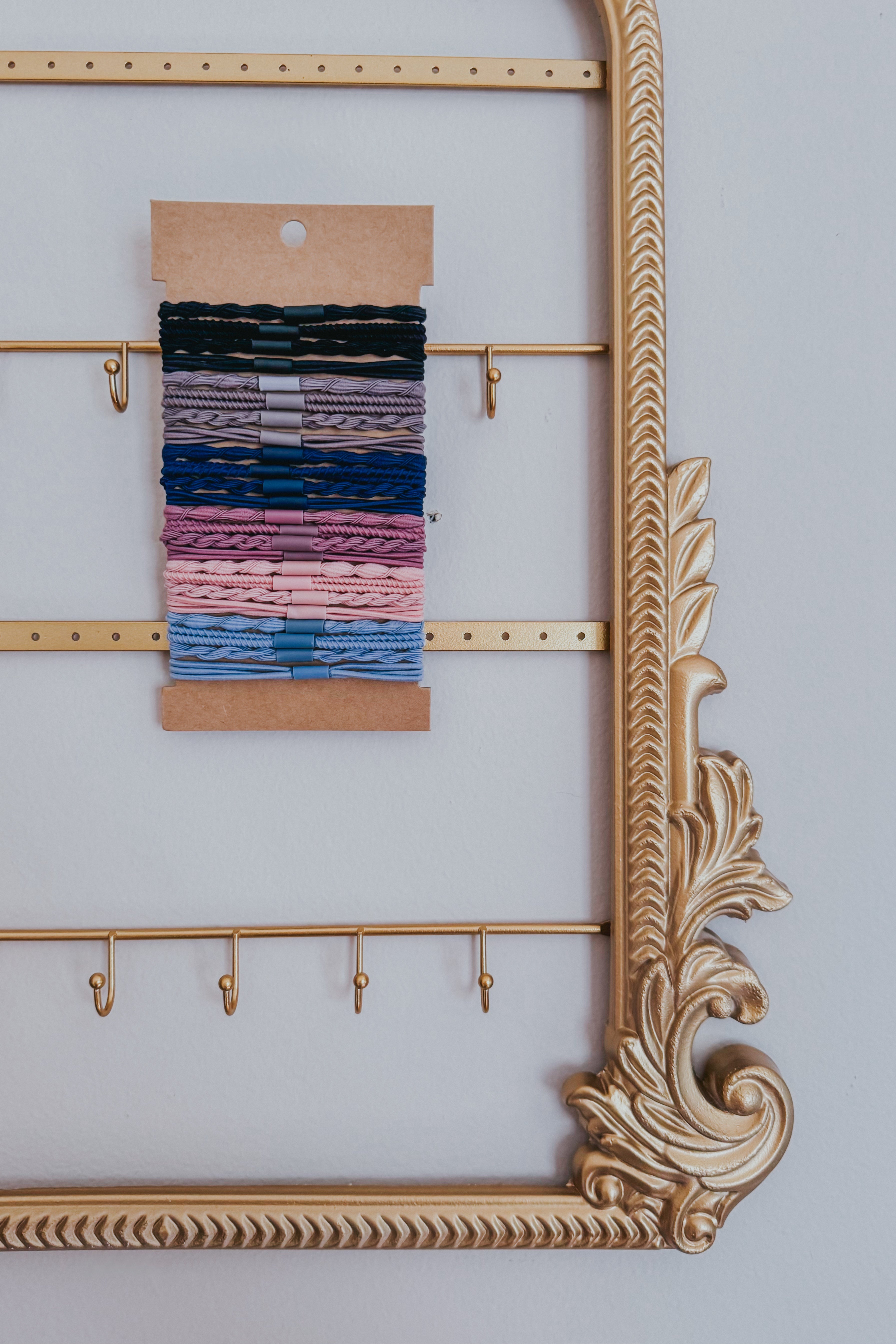 Assortment of night sky toned hair tie bracelets with braided and twisted details displayed on kraft card within gold ornate frame