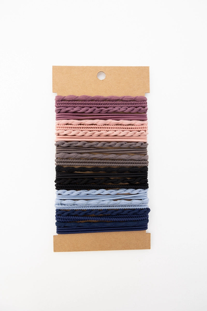 Set of textured stackable hair ties in night sky tones, including shades of purple, pink, gray, black, and blue on kraft card