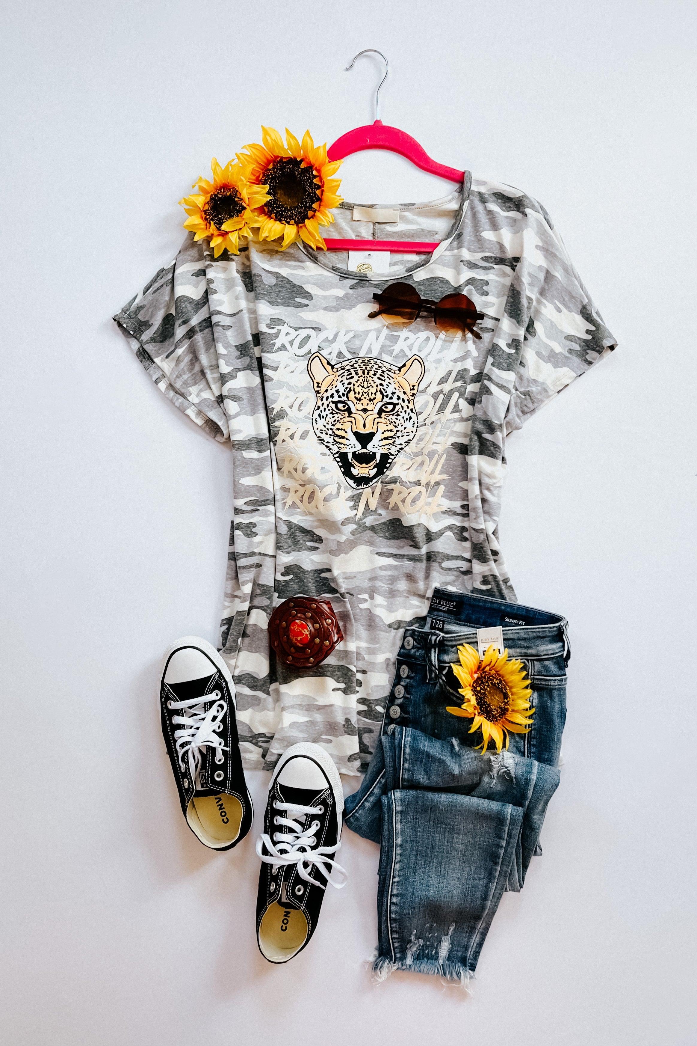 Grey camo tee with bold leopard graphic paired with distressed denim jeans, black sneakers, and sunflower accents on white background