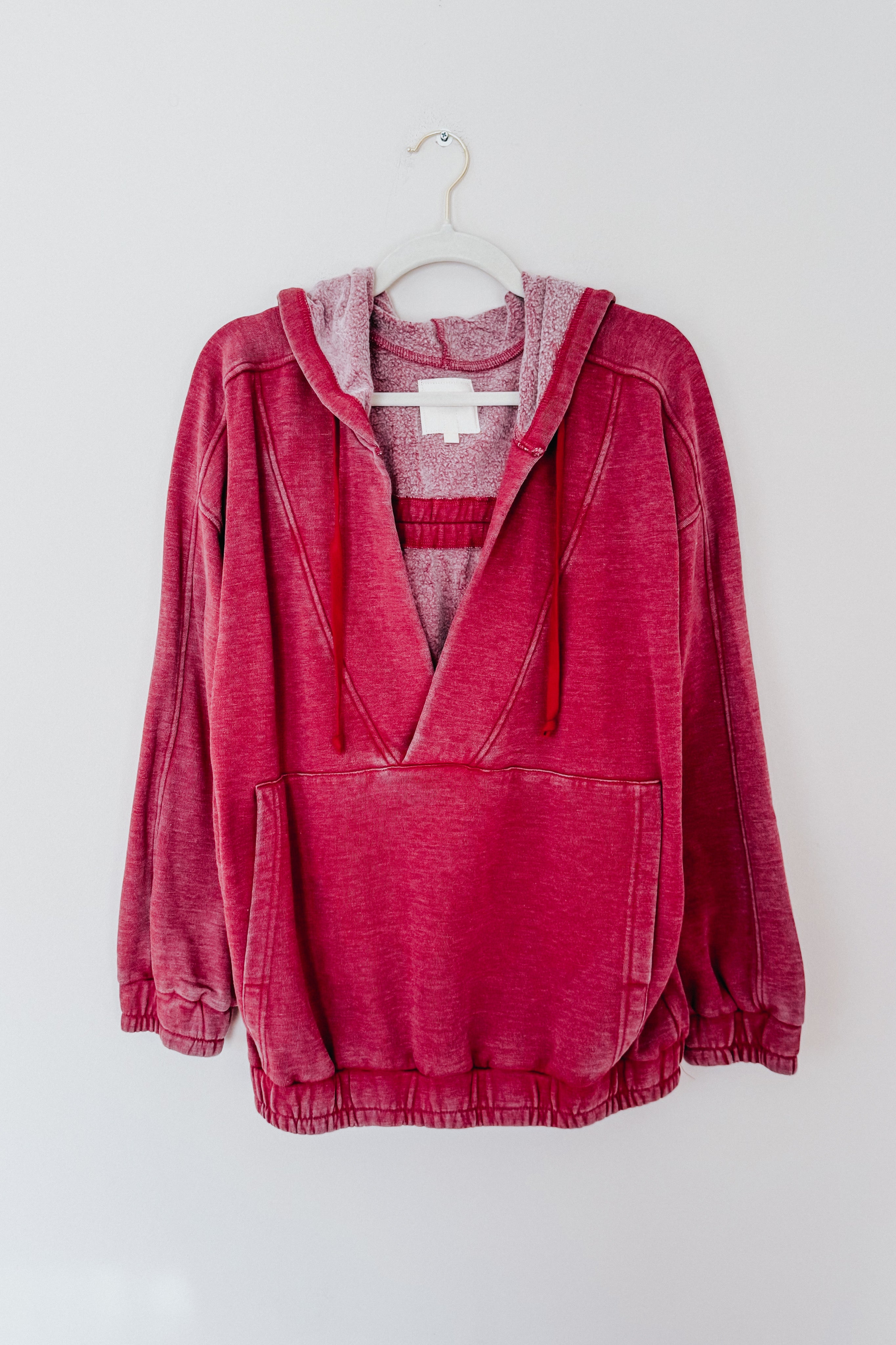 Wine-colored acid wash hoodie with plush lining, kangaroo pocket, and drawstring hood hanging on white hanger
