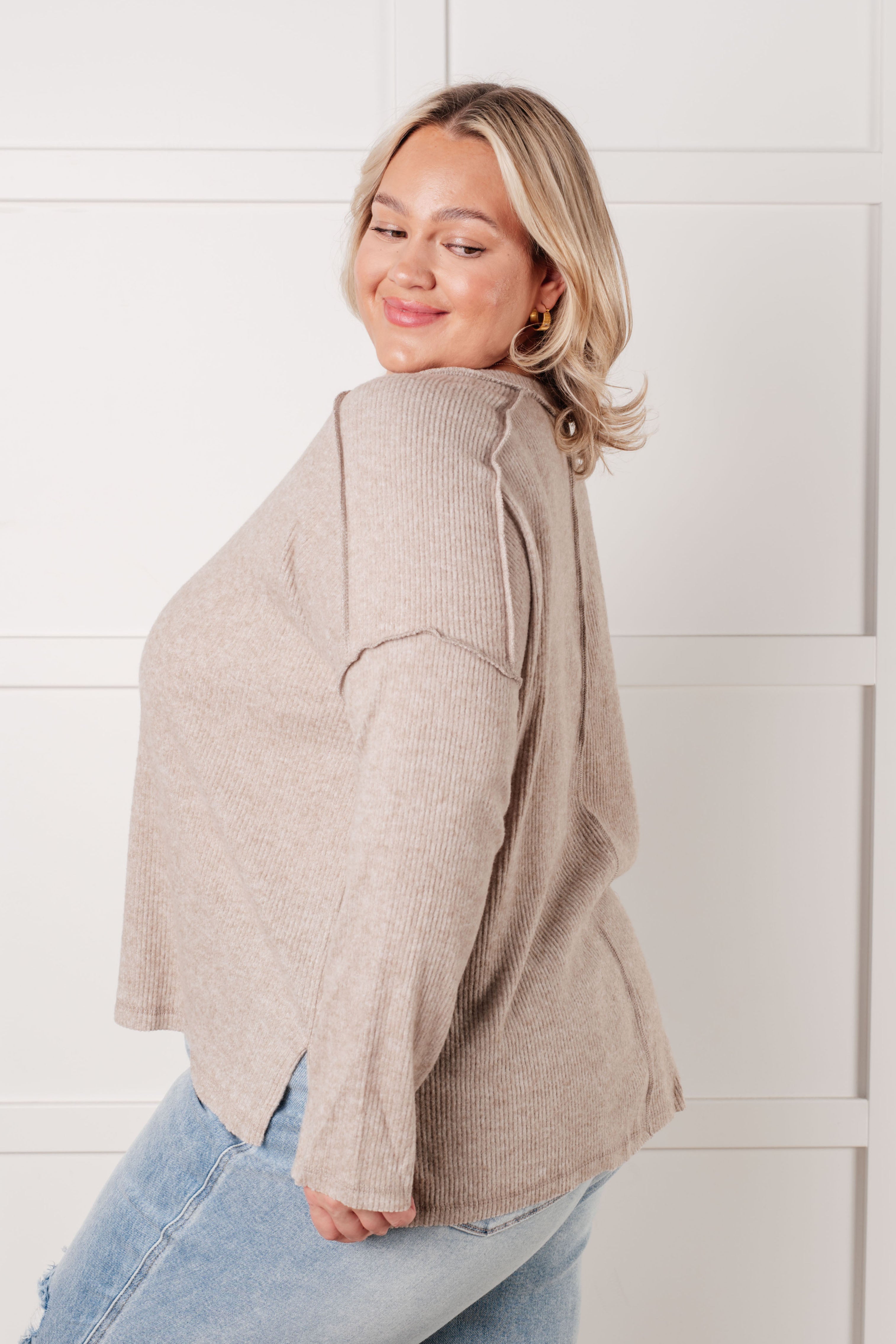 Smiling woman wearing relaxed fit ribbed hacci sweater in soft heather mocha with light wash jeans indoors