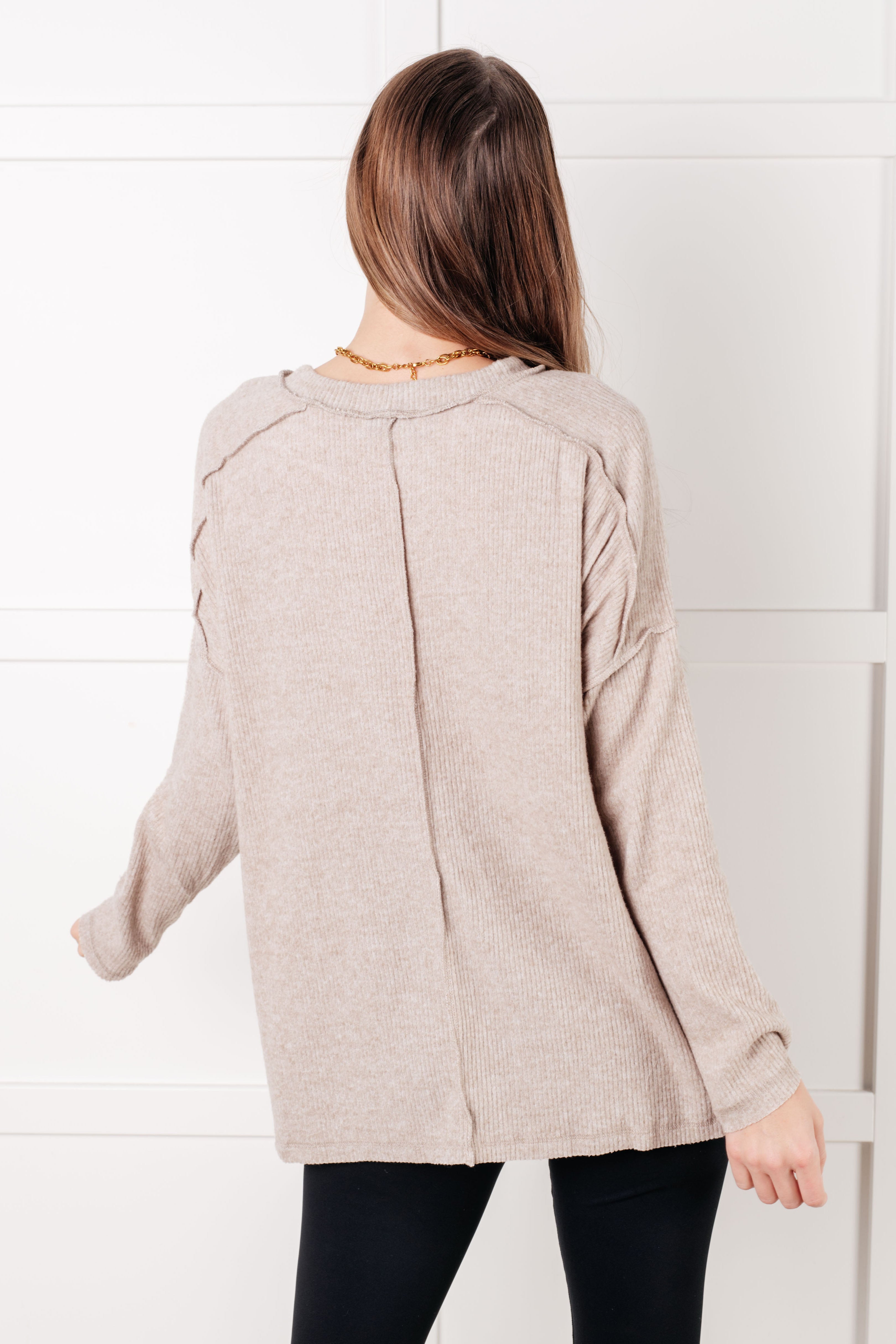 Back view of woman wearing loose heather mocha ribbed sweater with long sleeves and relaxed fit