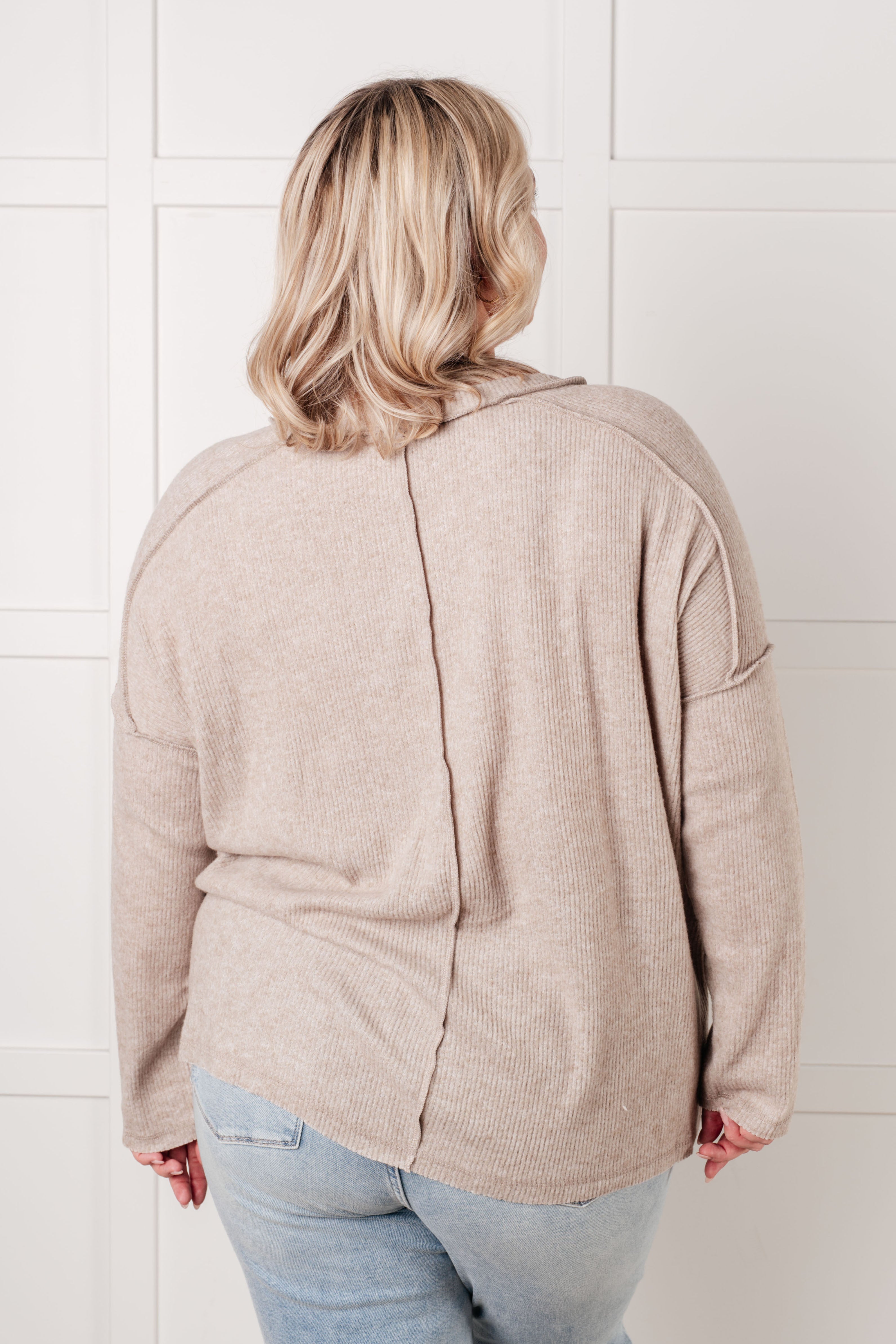 Plus-size woman wearing relaxed ribbed mocha sweater with seam detail down the back paired with light wash jeans